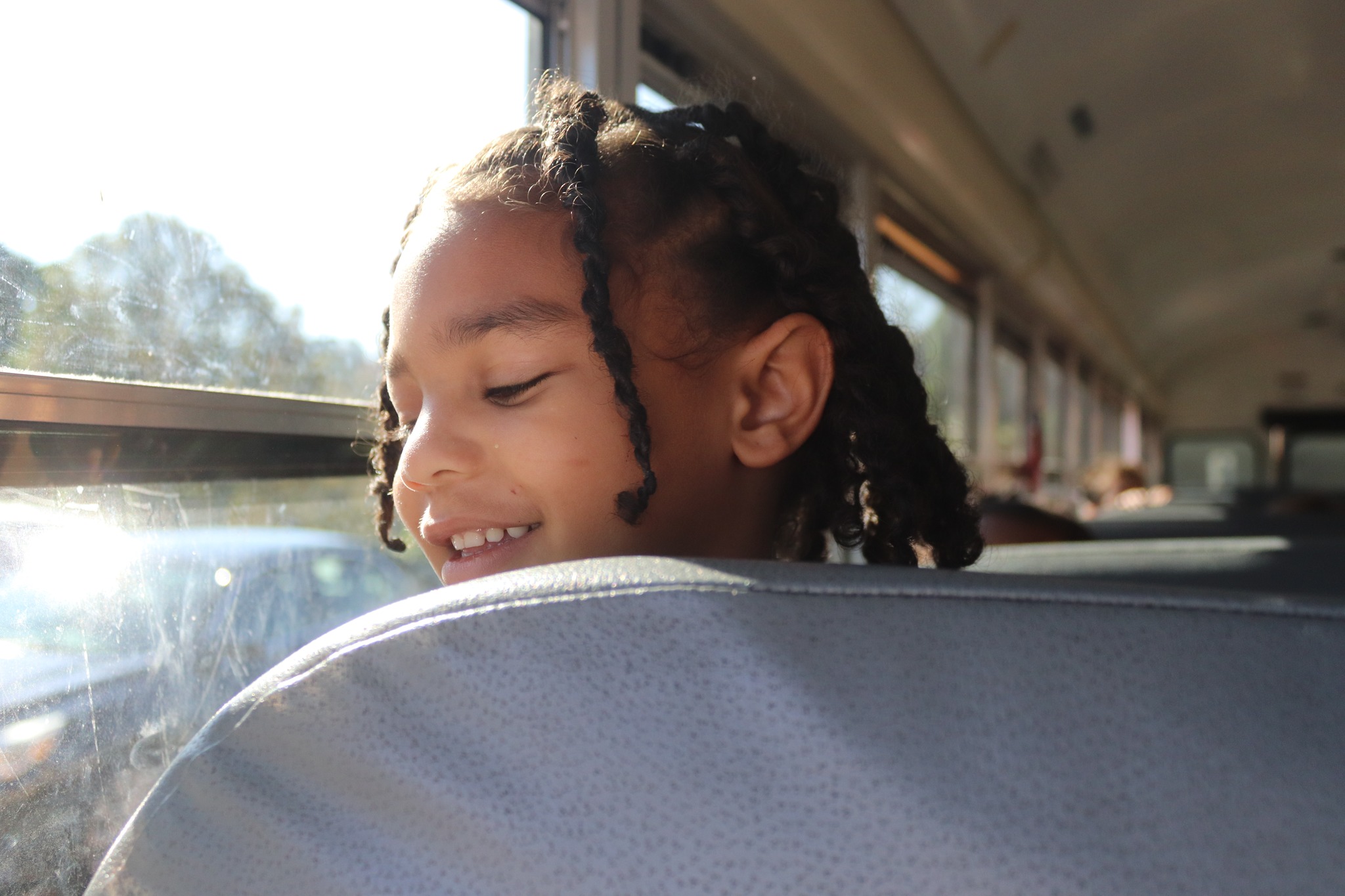 A student peers over a bus seat