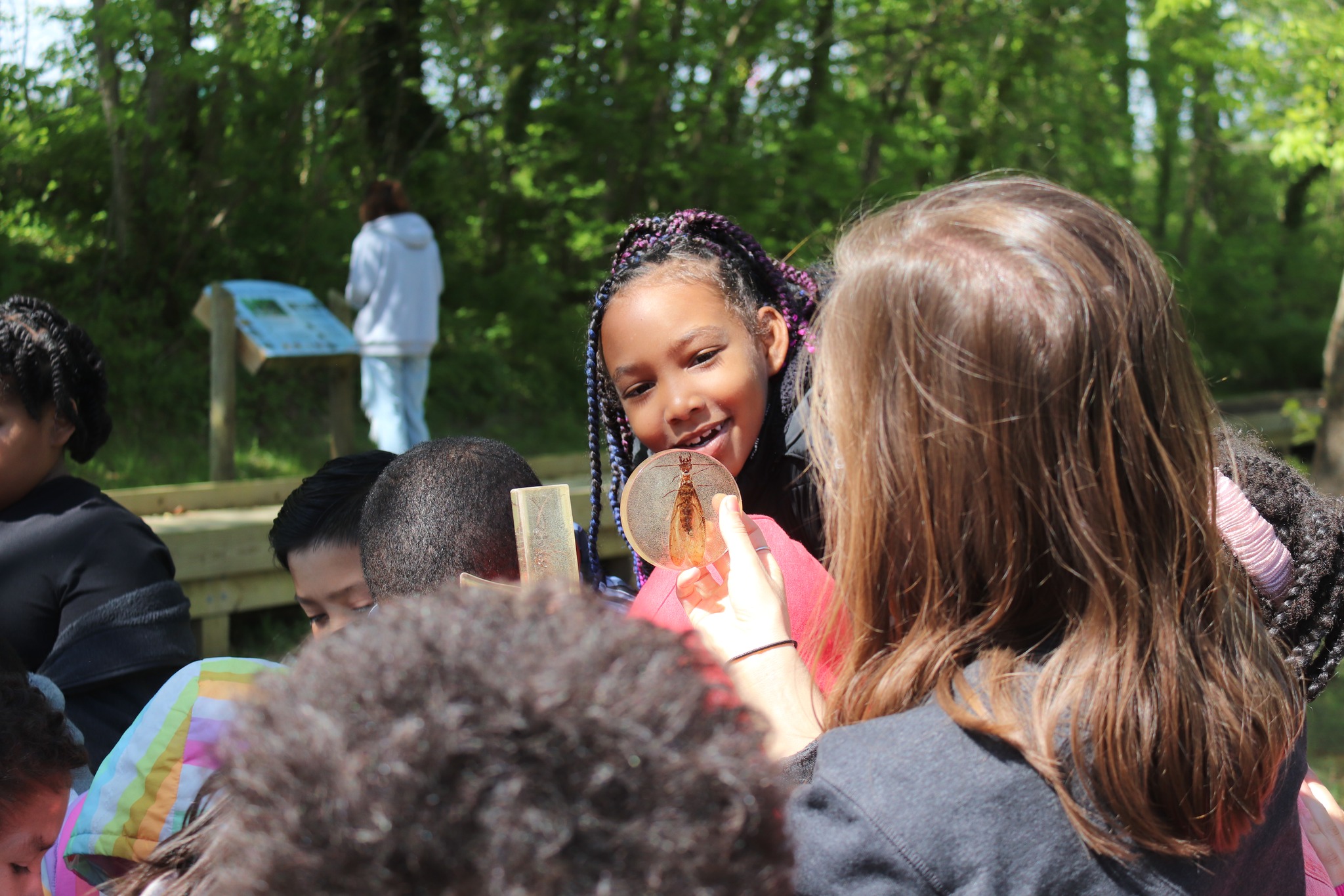 AHES student smiles as an instructor holds up a macro invertebrate
