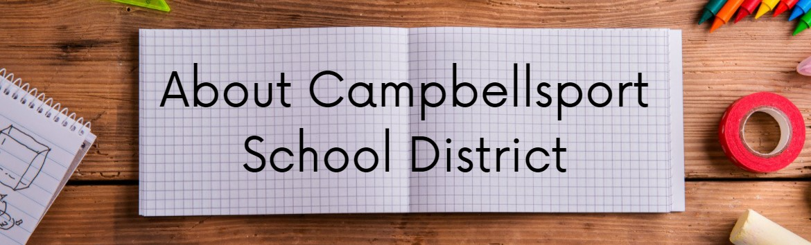 About Camballsport School District written on graph paper on a wooden desk with school supplies laying around it