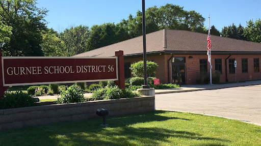 A building with a sign reading "Gurnee School District 56" in front of a grassy area.