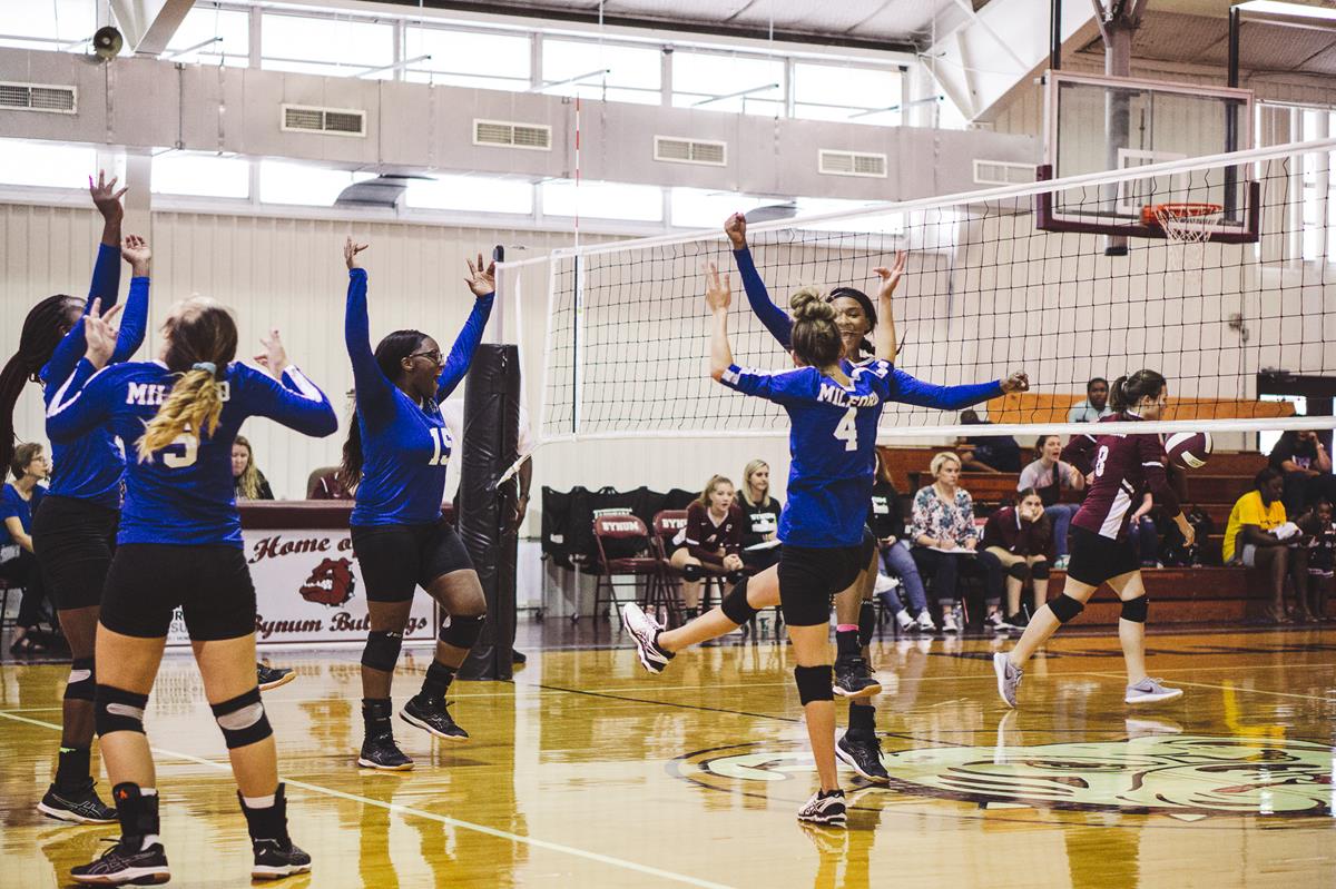 Volleyball team celebrating on court.