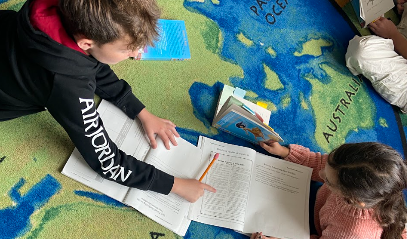 students on rug writing in notebooks