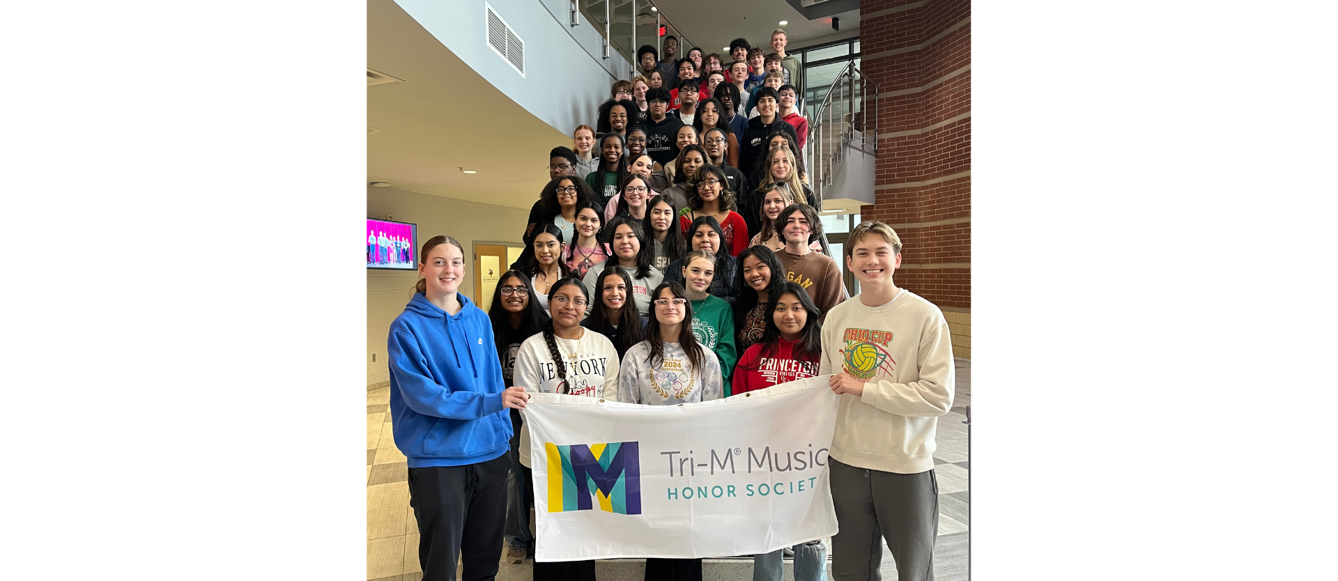 Students selected to be in the Tri-M honor society with banner