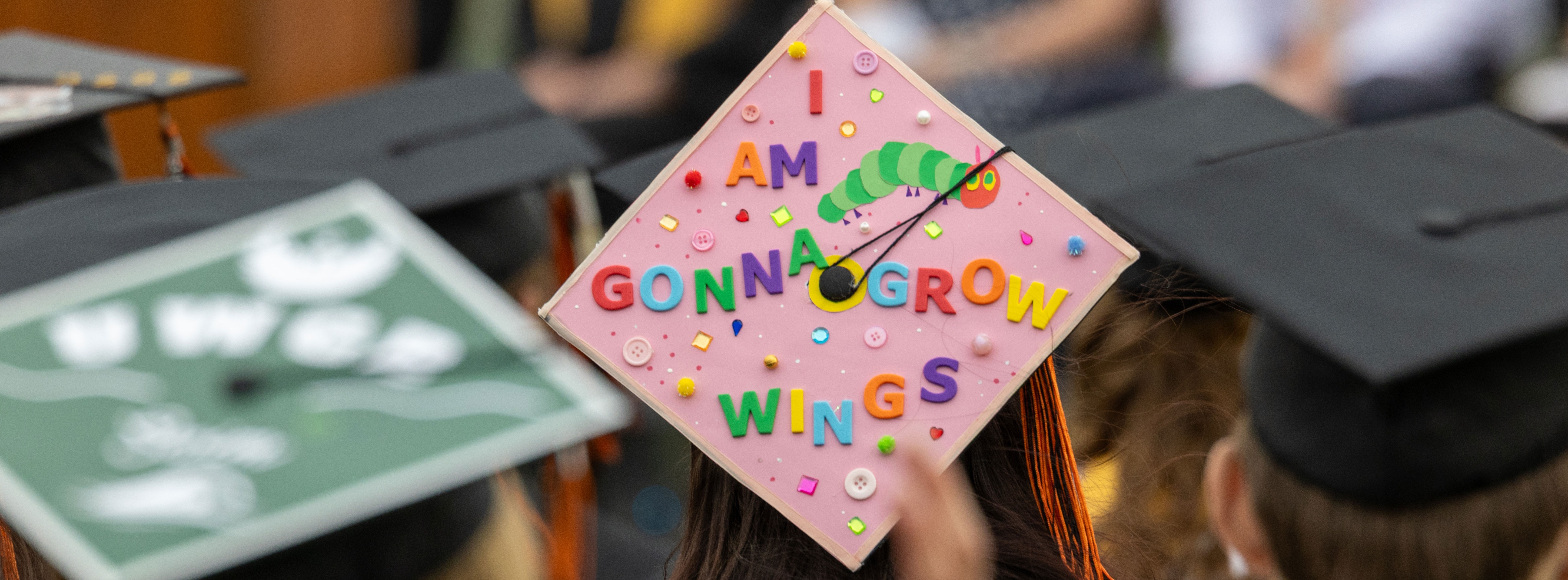 Grad cap decorated in letters that say "I am gonna grow wings"