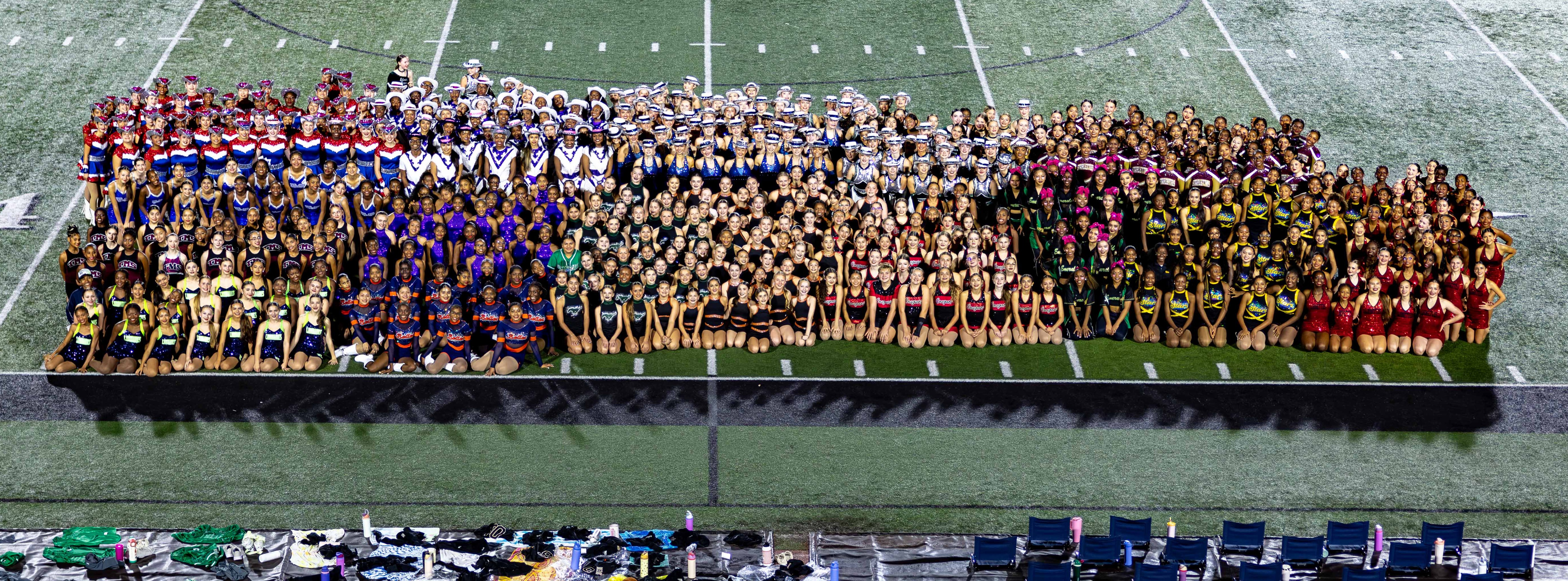 Large crowd watching a school event on a football field, students forming a large shape.