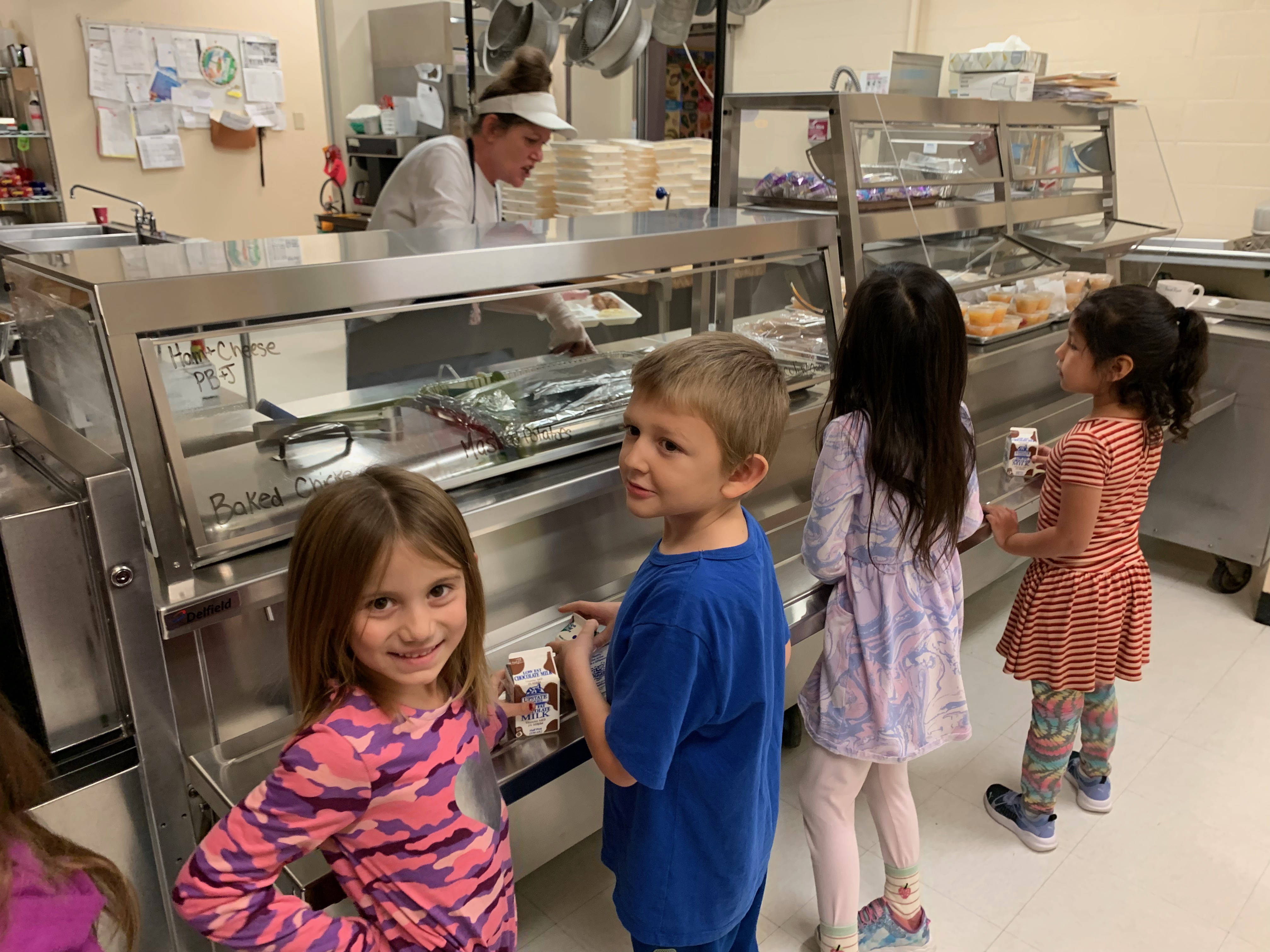 Elementary school students stand in the lunch line, ready to be served by a nice  lunch lady