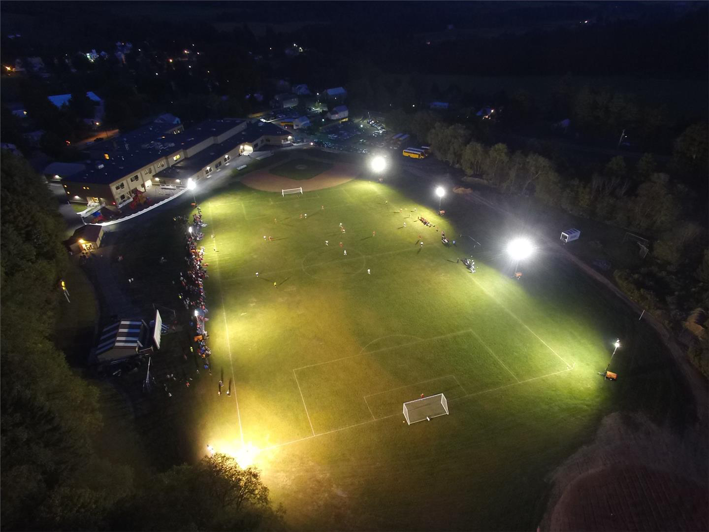 school athletic field with soccer players playing under the lights