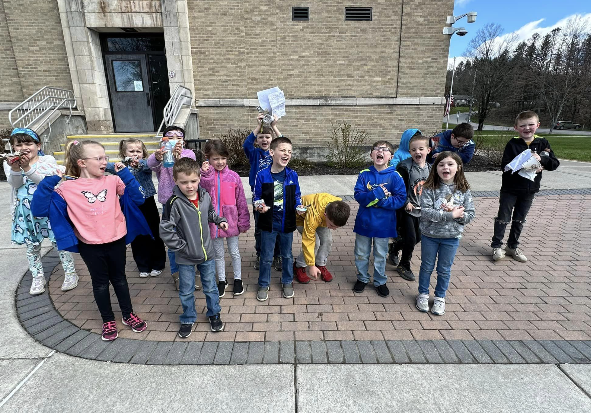Elementary students smile and shout after picking up garbage for Earth Day