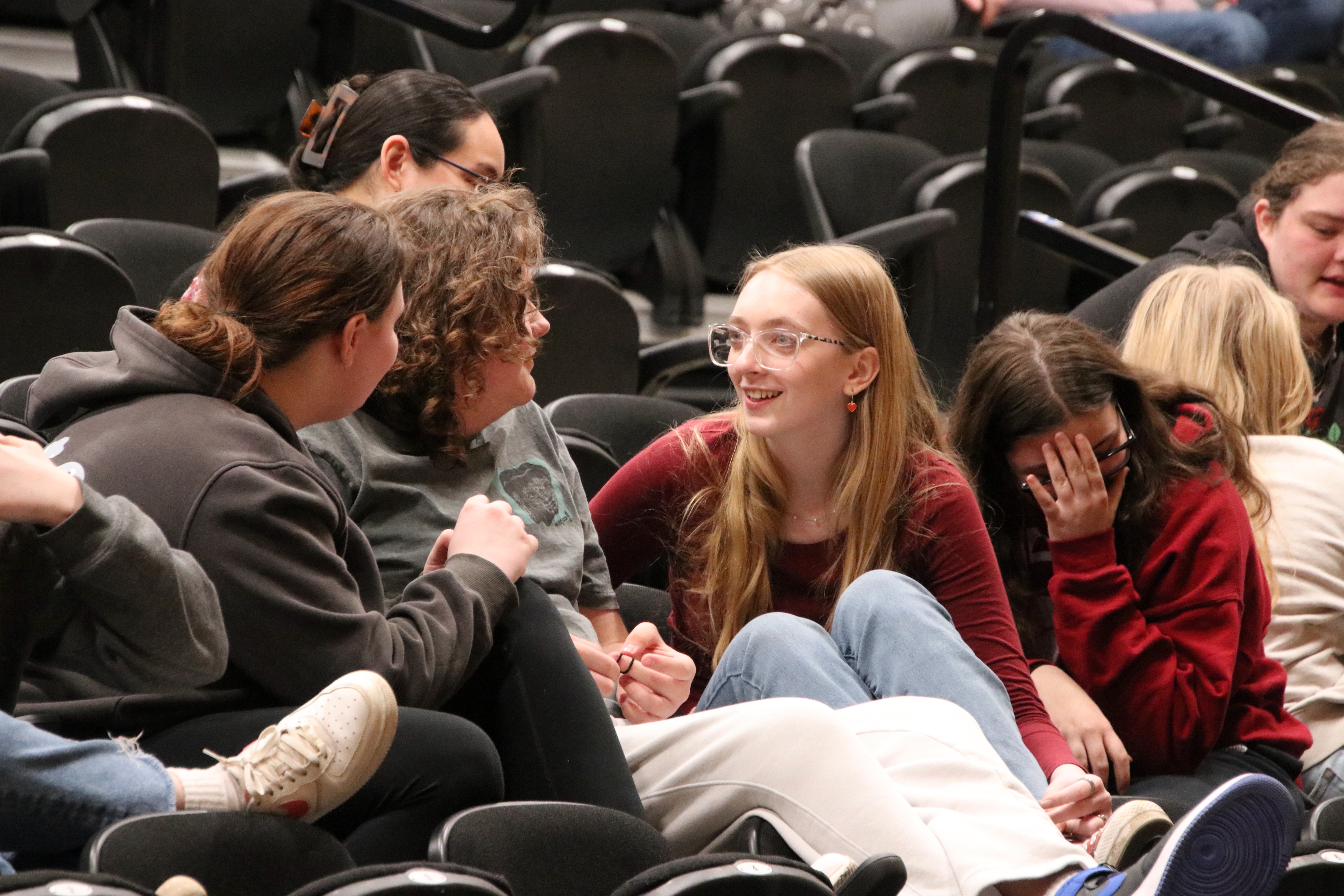 High school students laugh together while sitting in an auditorium