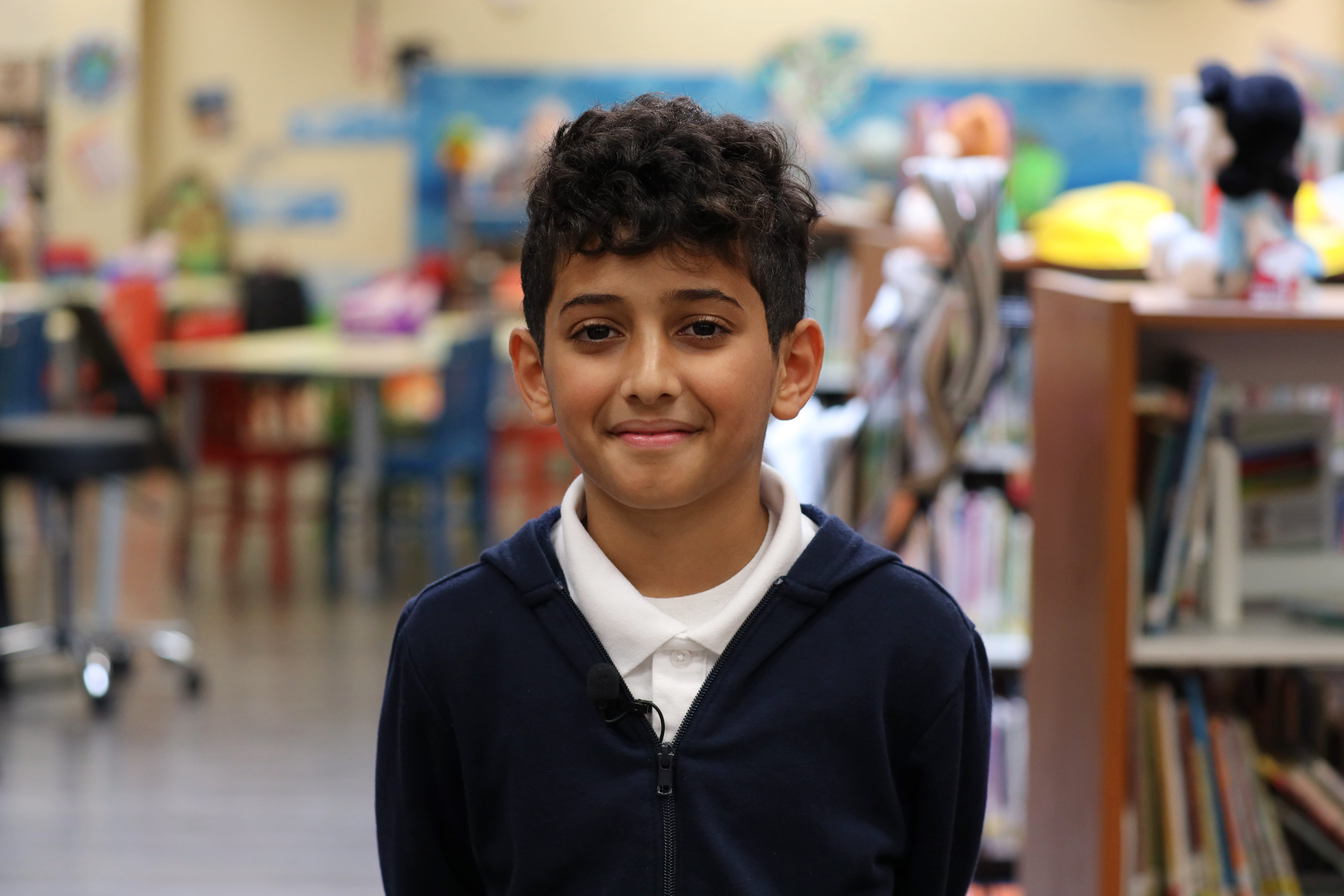 Hisam Saleh smiling while standing in the library at Warren Central Intermediate School.