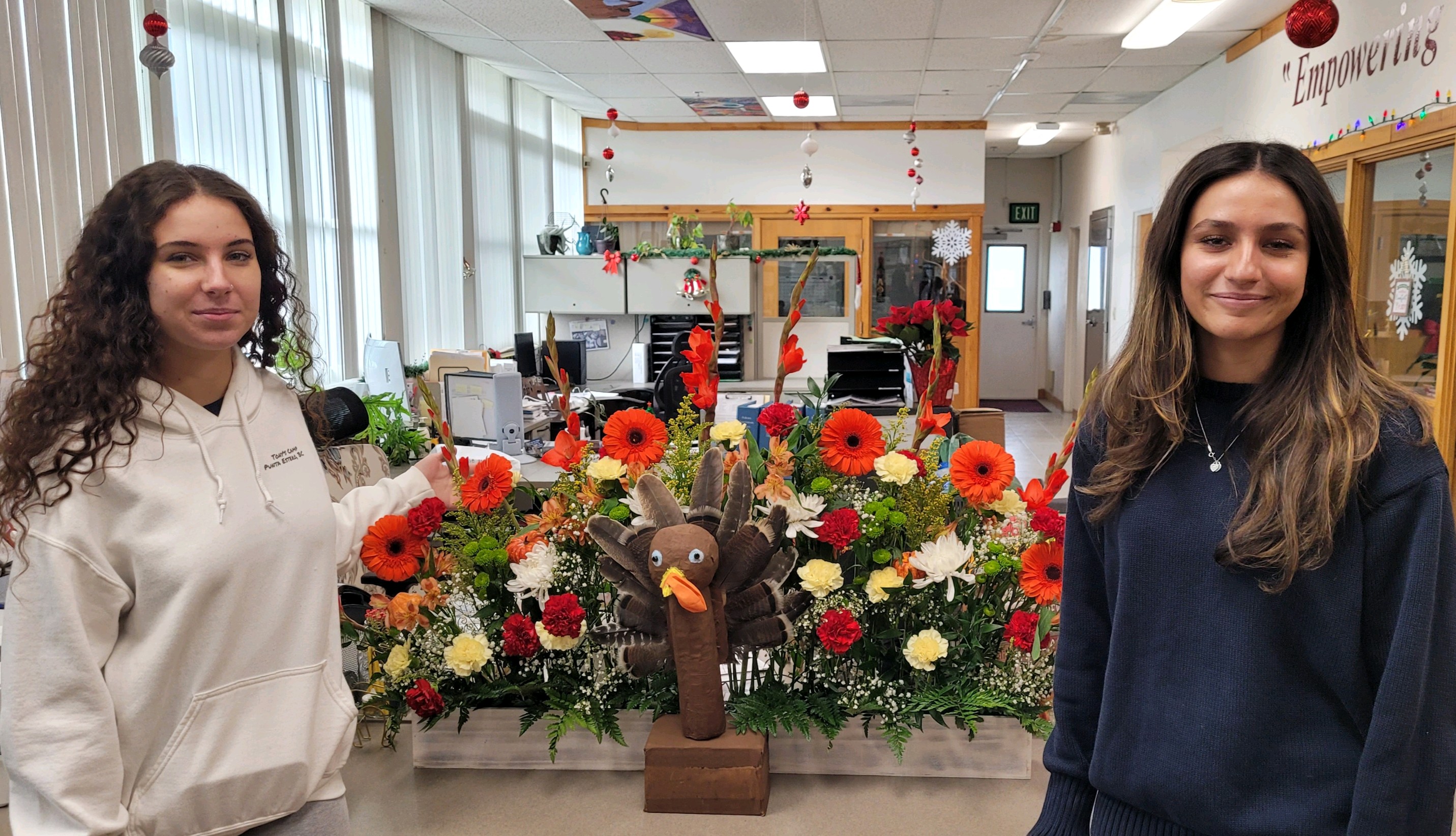 Female students pose with their Thanksgiving themed floral arrangement.