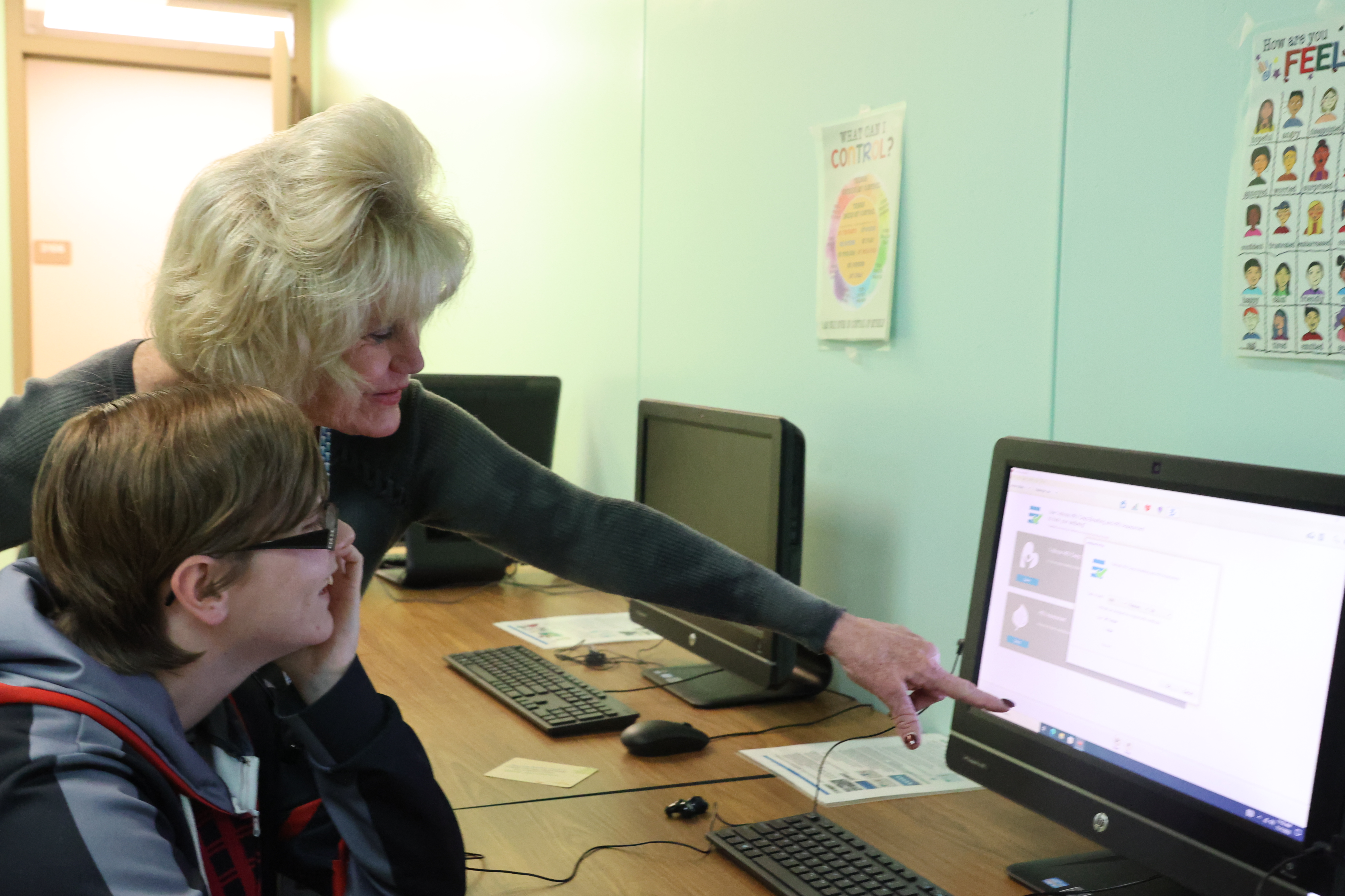 teacher helping a student on the computer