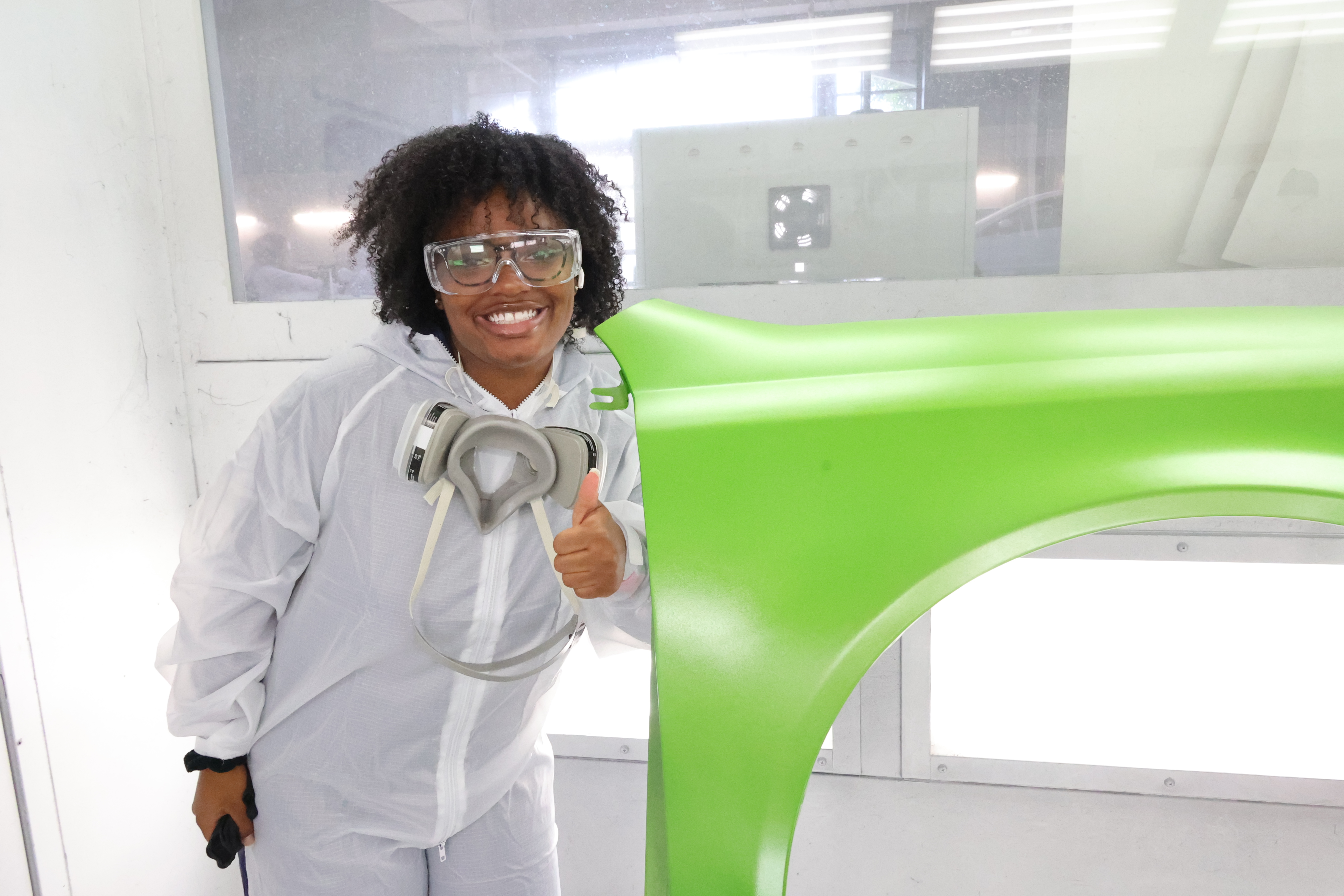 Black female student poses next to a fender she painted Lime Green