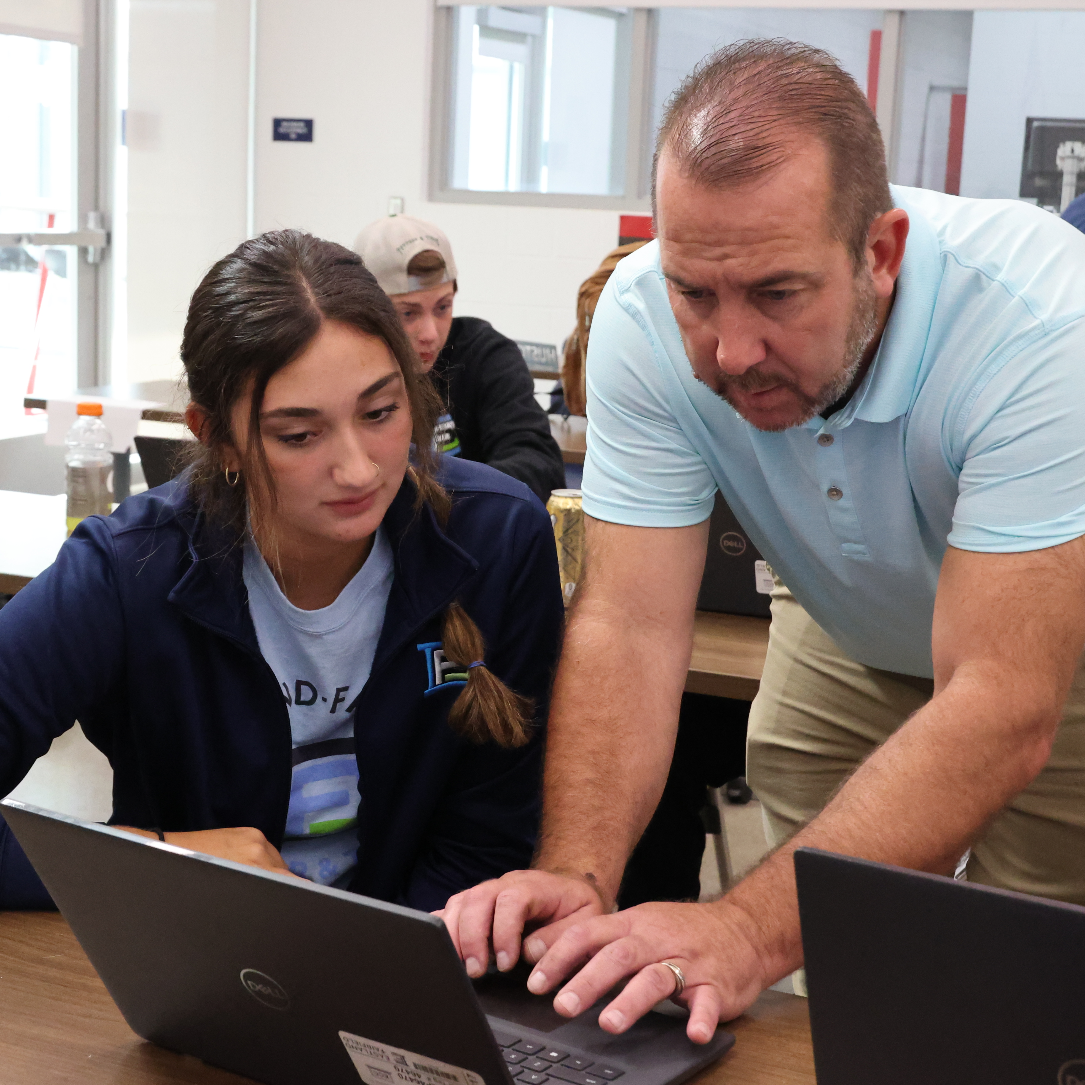 An instructor navigates a Chromebook with a female student