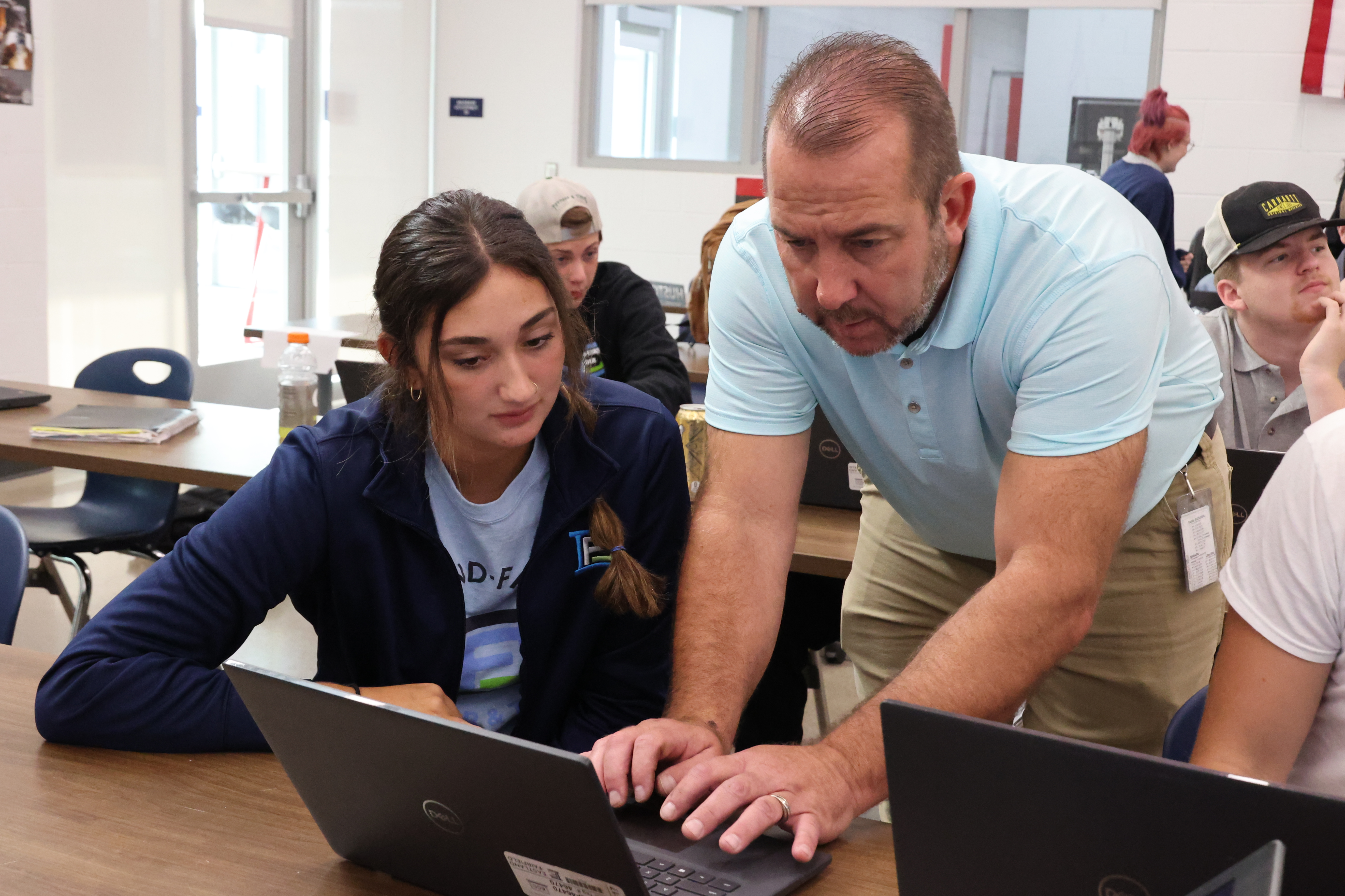 An instructor is helping a female student navigate her Chromebook