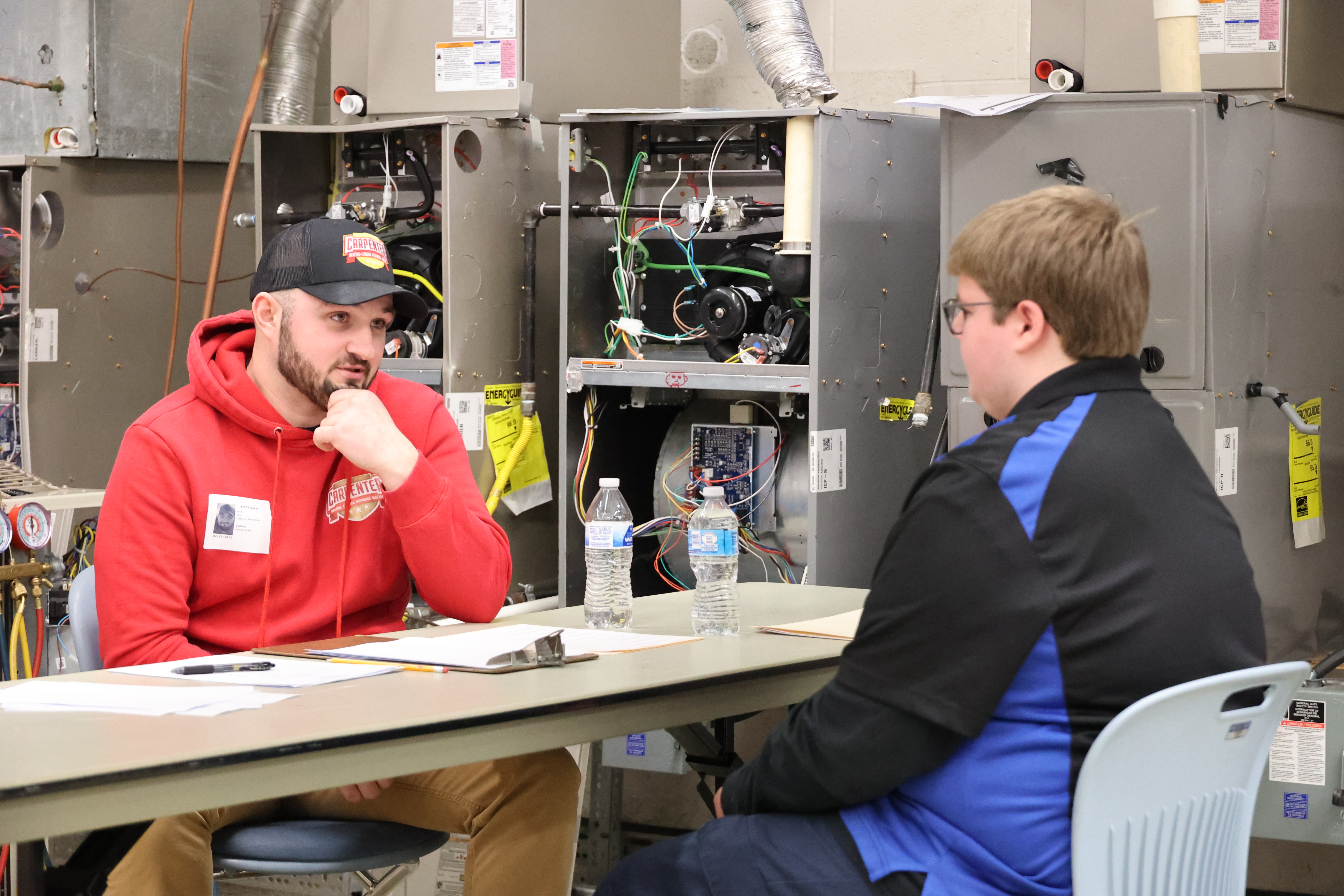 A member of the Carpenter Heating & Cooling staff sits down across the table from an EFCTS HVAC student in a job interview setting.