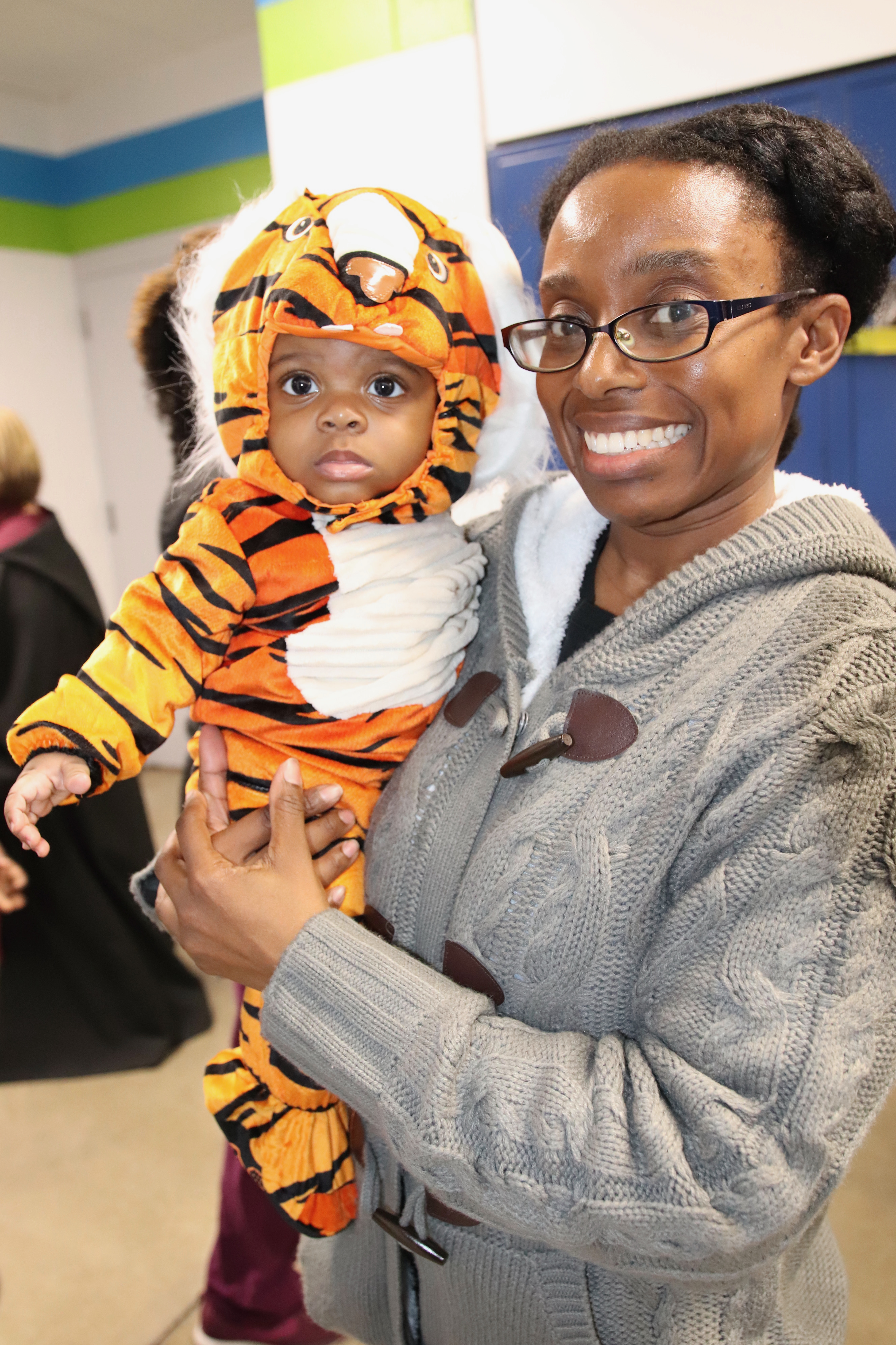 A small child in a tiger costume with their mother.