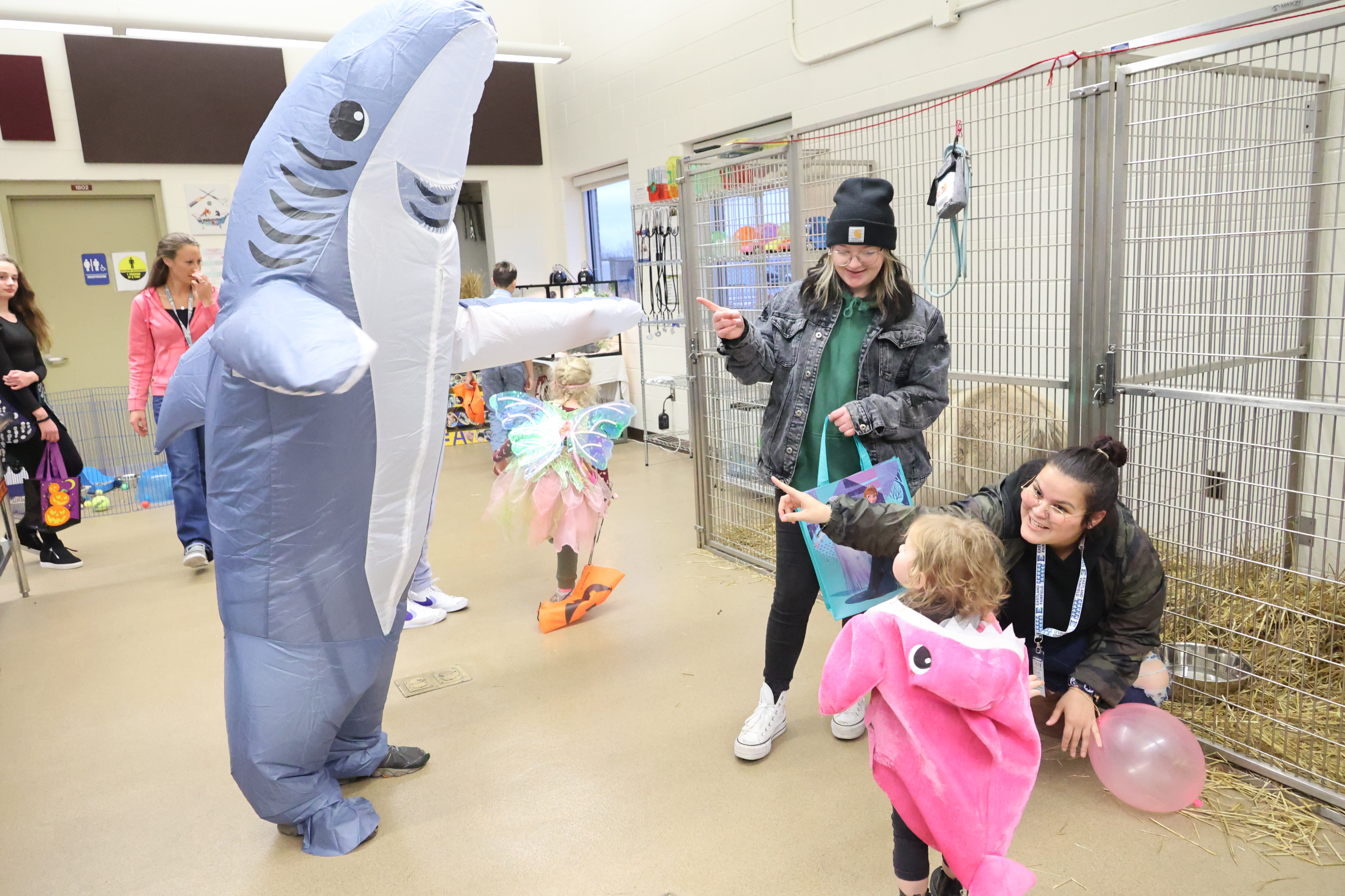 A person in a shark costume meets a young child in a baby shark costume!