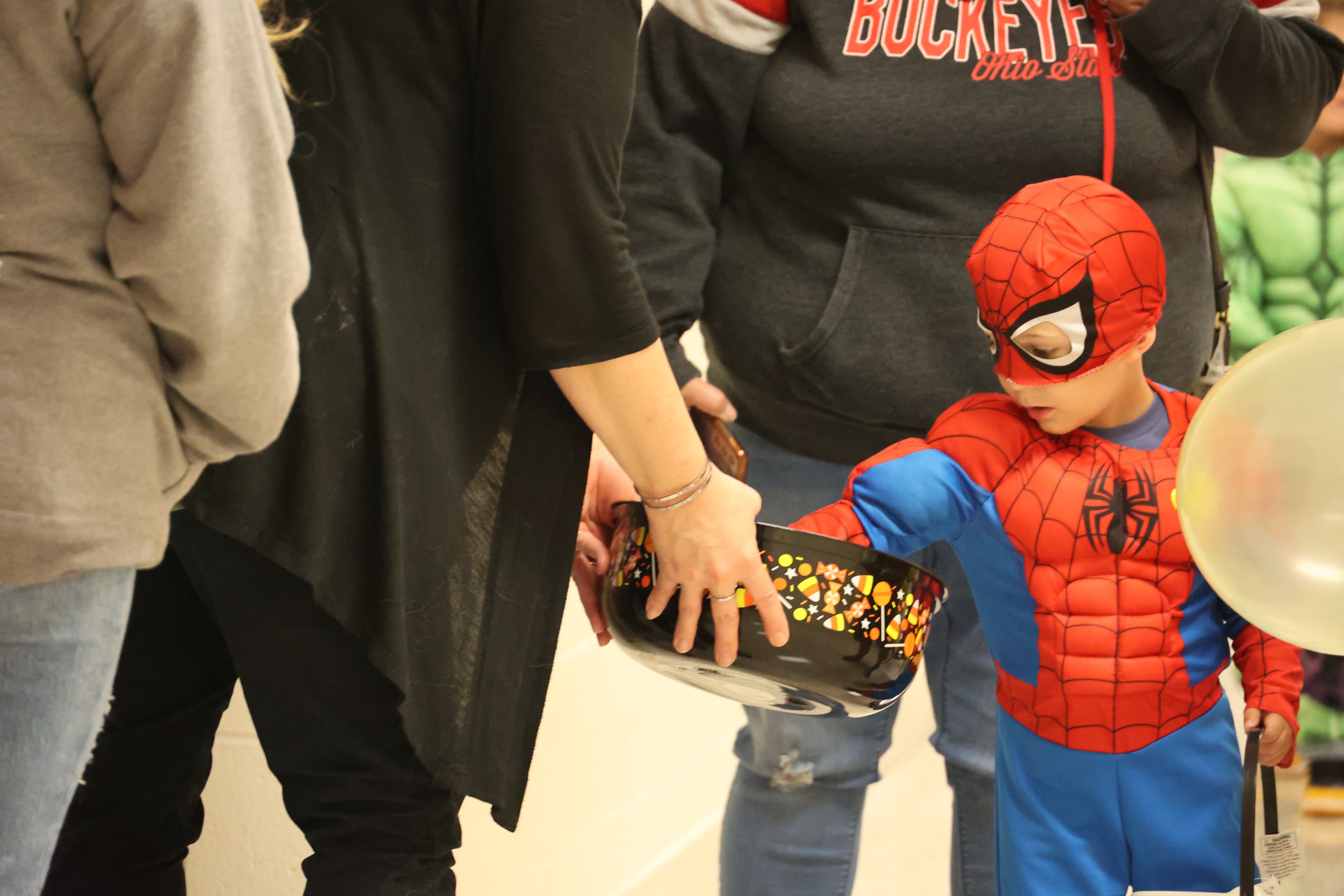 A child dressed as Spiderman reaches for candy.