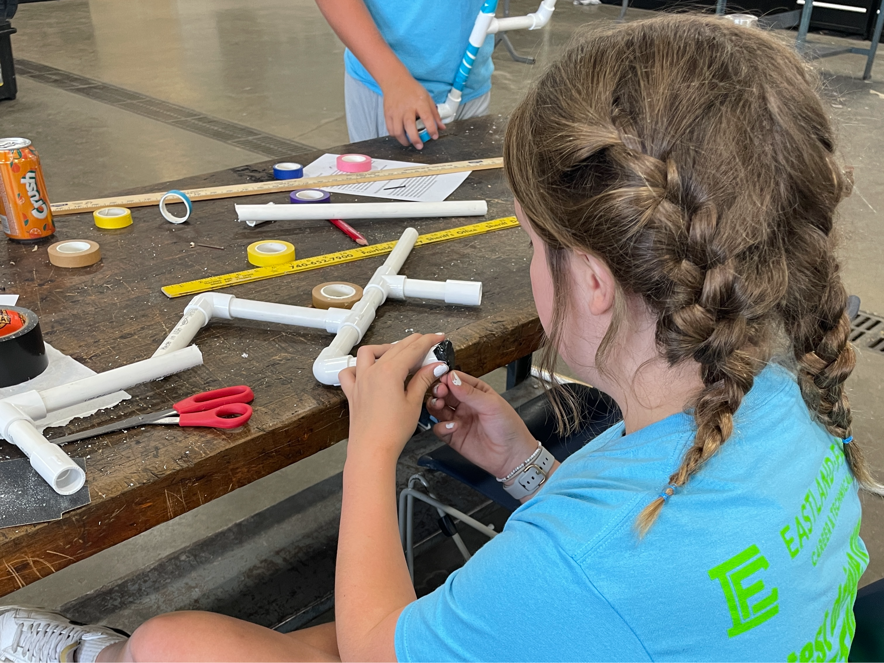 Female summer camper does an activity with PVC pipe