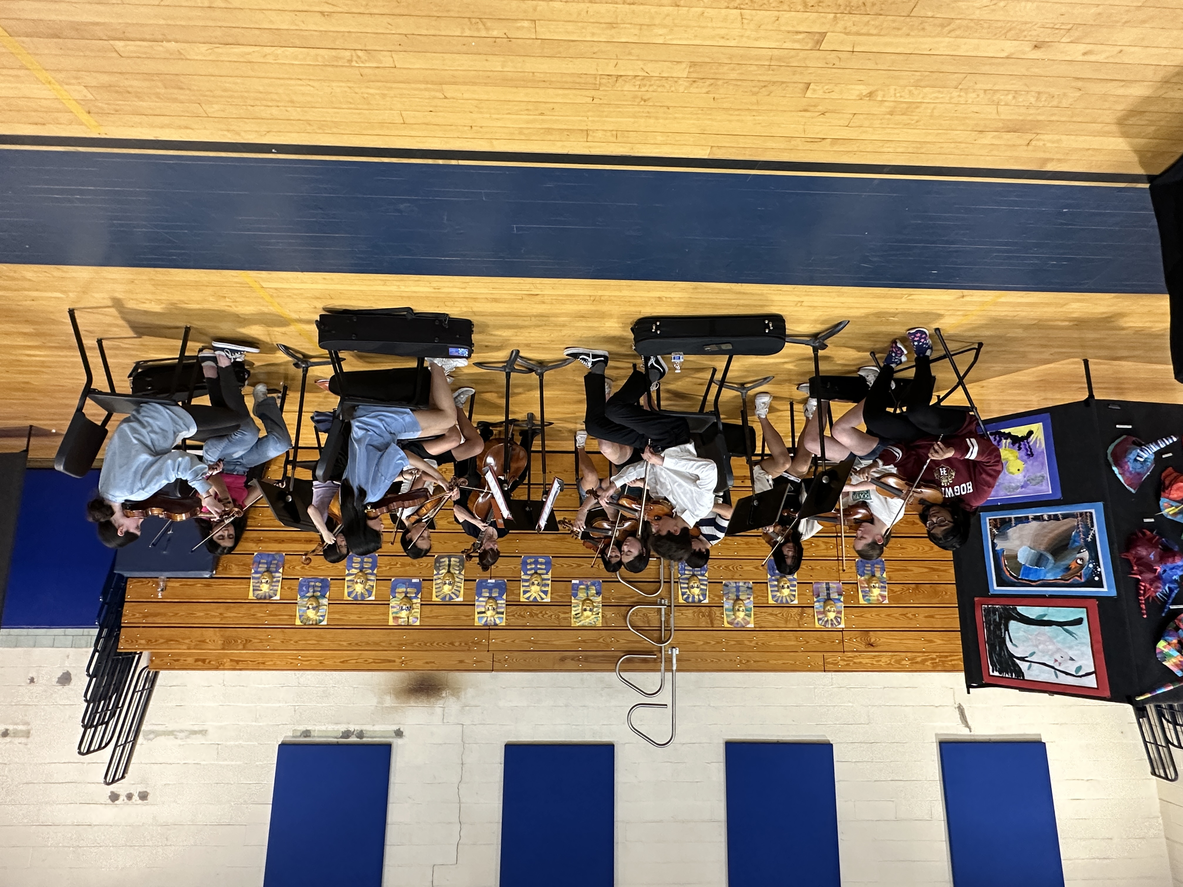 students playing orchestra in gym with panels behind them
