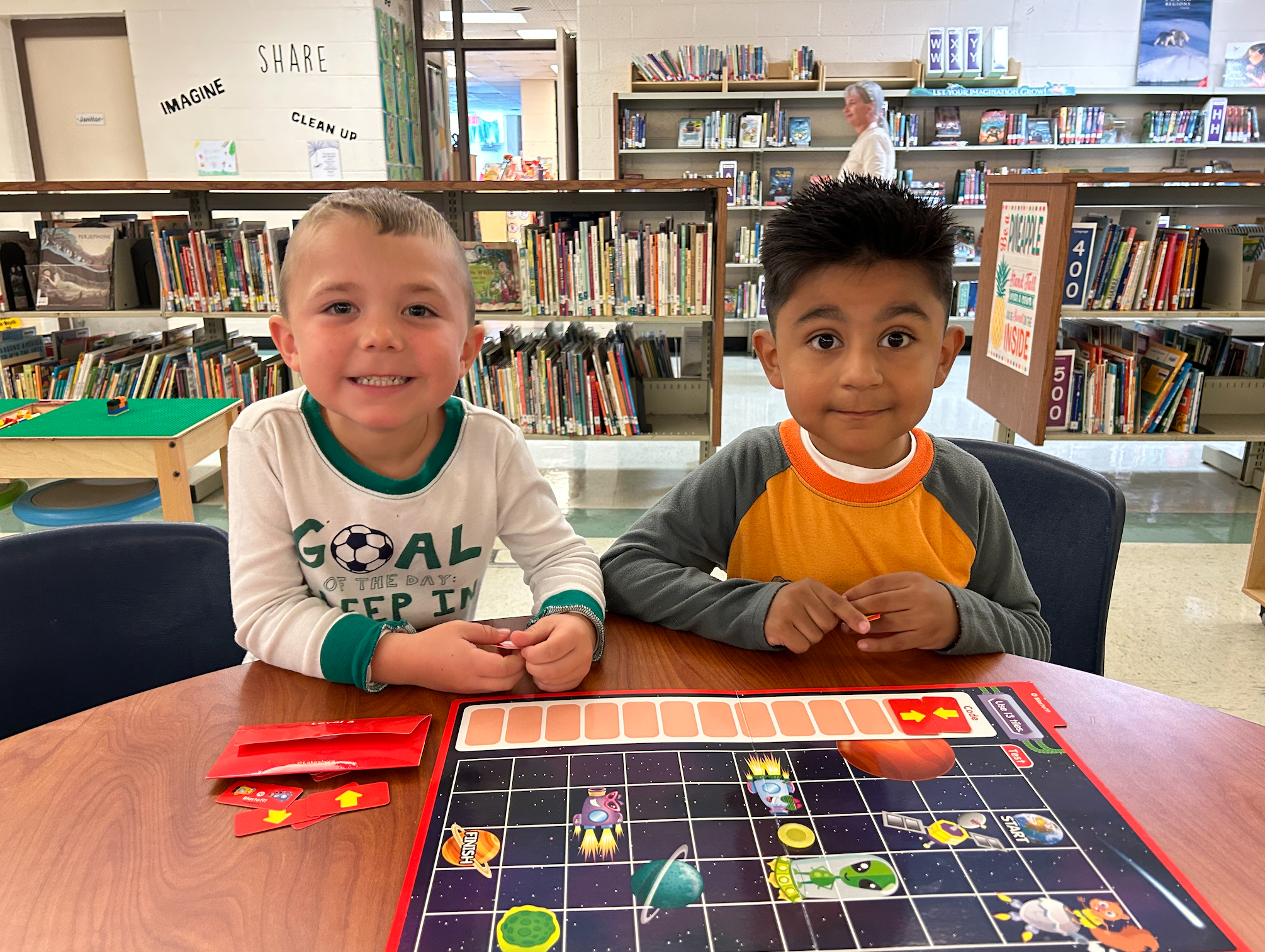 Two students seated at table playing a coding game in the library.