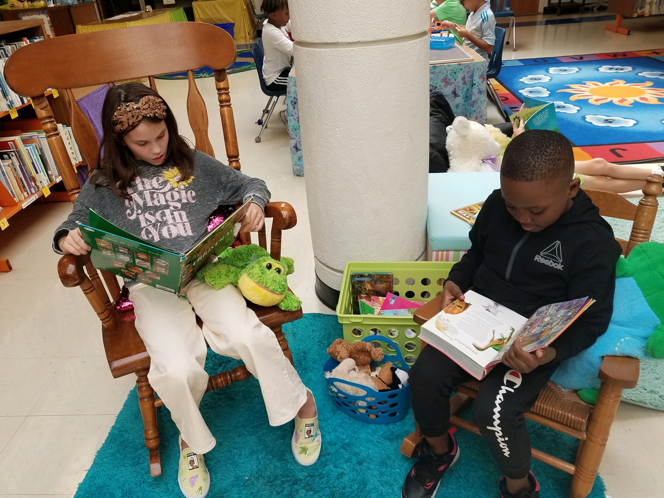 Two students in rocking chairs reading in the library.