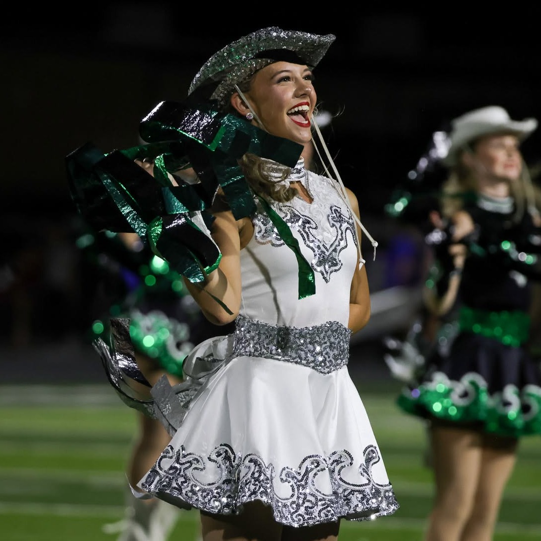 girl wearing white dress and silver hat holding green pompom