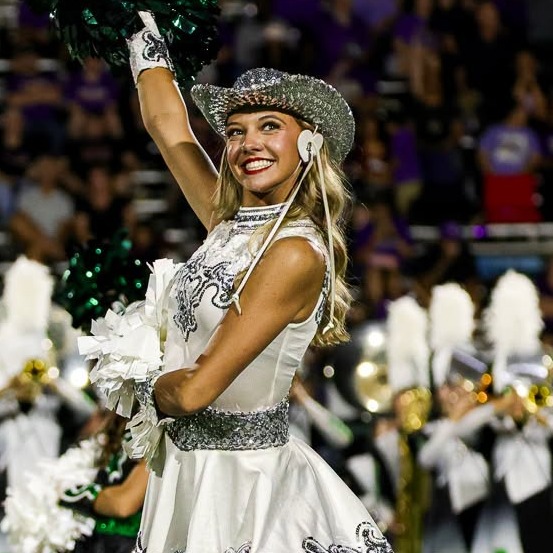girl wearing white dress and silver hat holding green pompom