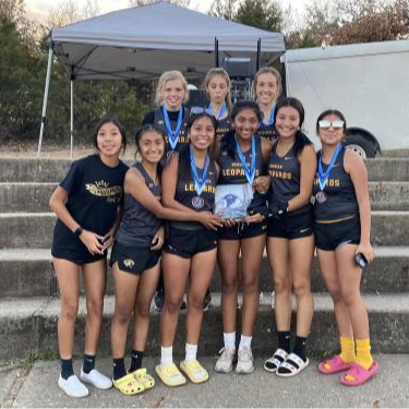 cross country team group picture outside with their medals