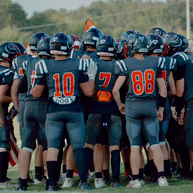 Cardinal Huskies Football team gathers together for a pregame huddle. 