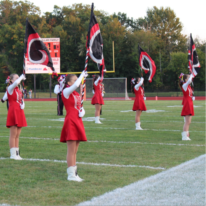 The Cardinal Silks Flag Line stand at attention, before a performance at the football game on Friday night. 