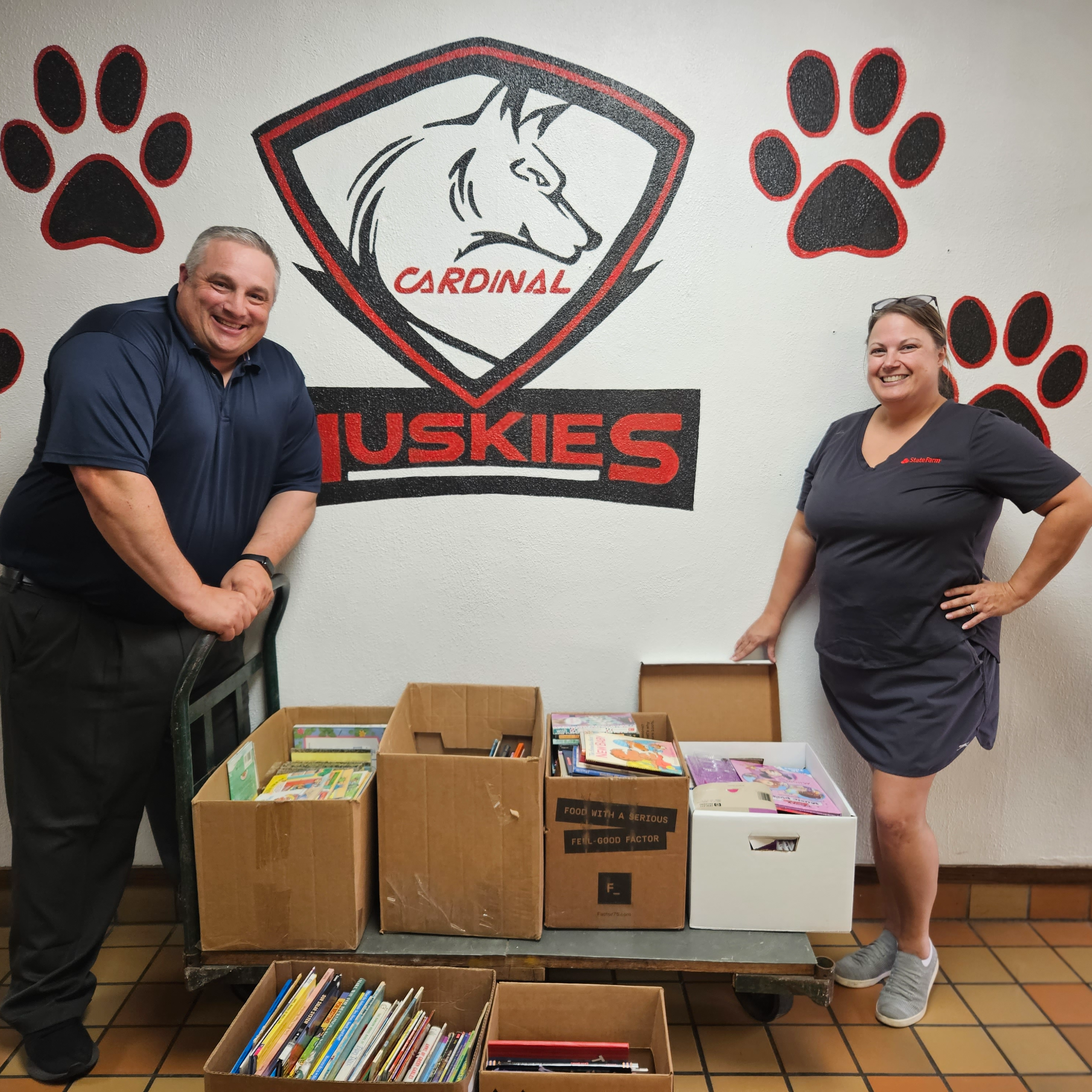 Mr. Kujala and a representative from State Farm pose with boxes of book donations.