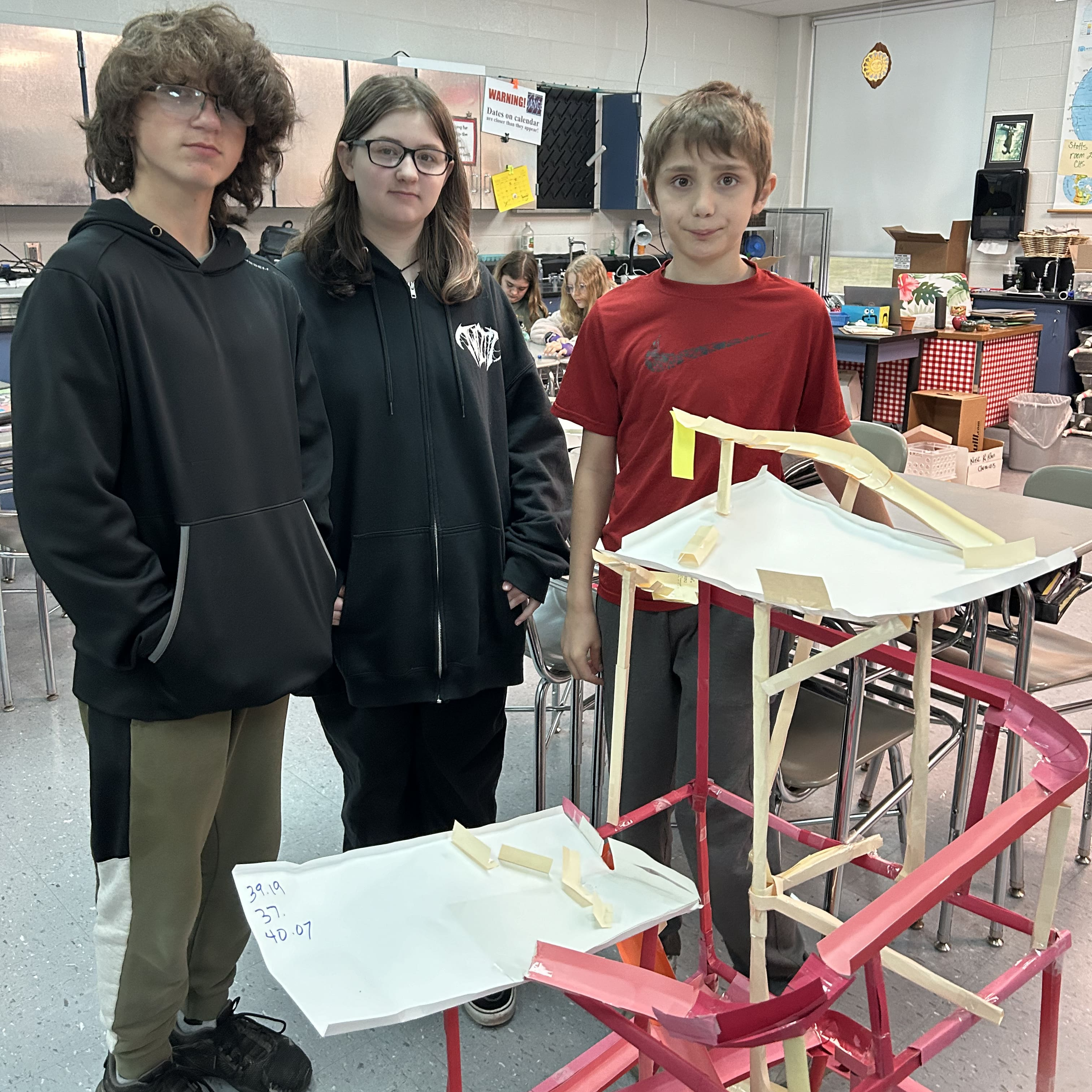 Middle School Students pose in front of their roller coasters that they built.