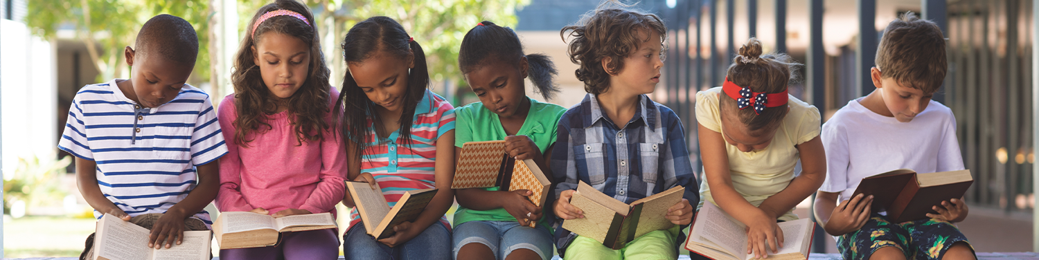 Group of kids sitting on a bench reading books