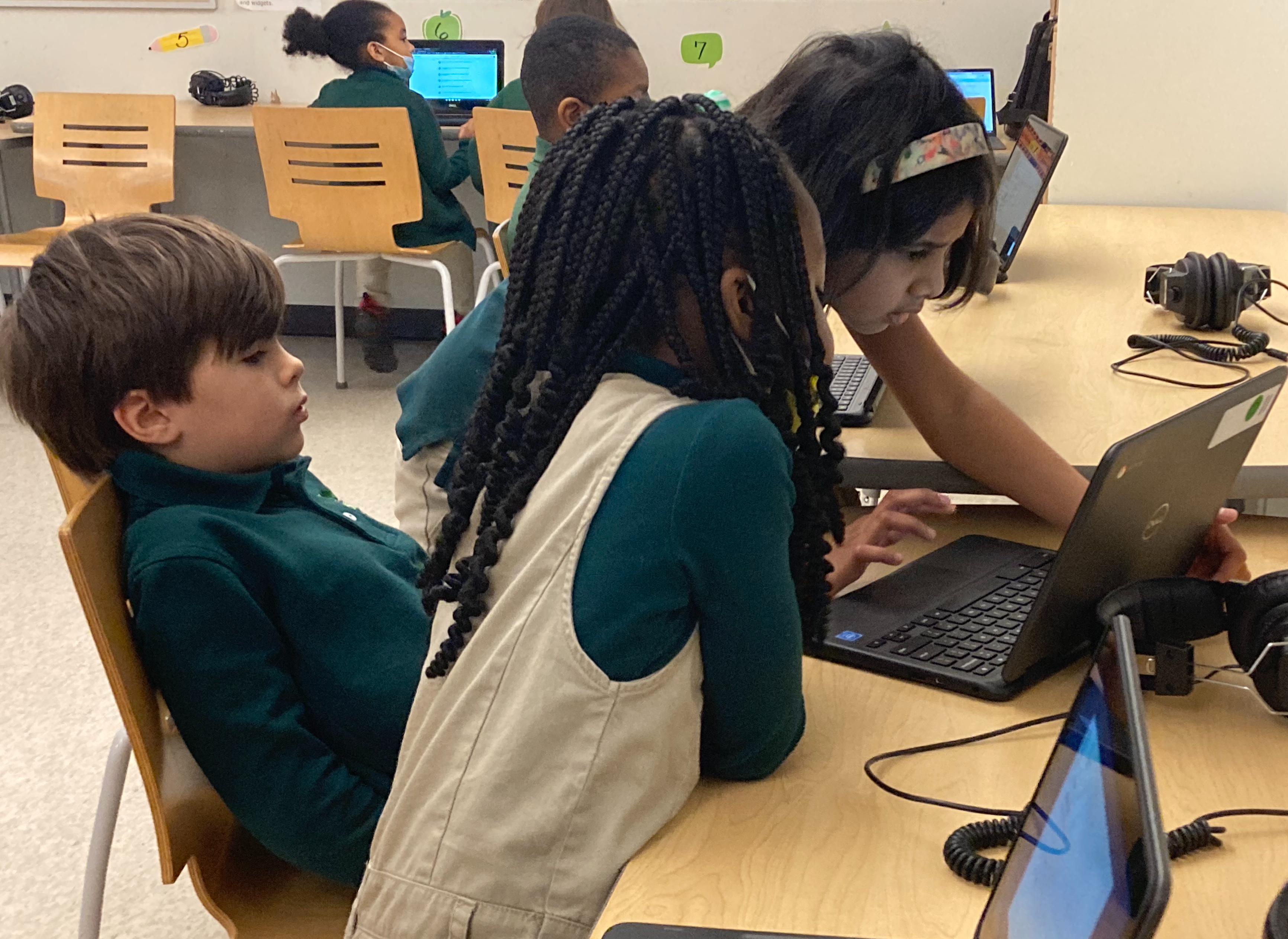 Three Elementary Students Collaborating on a Laptop