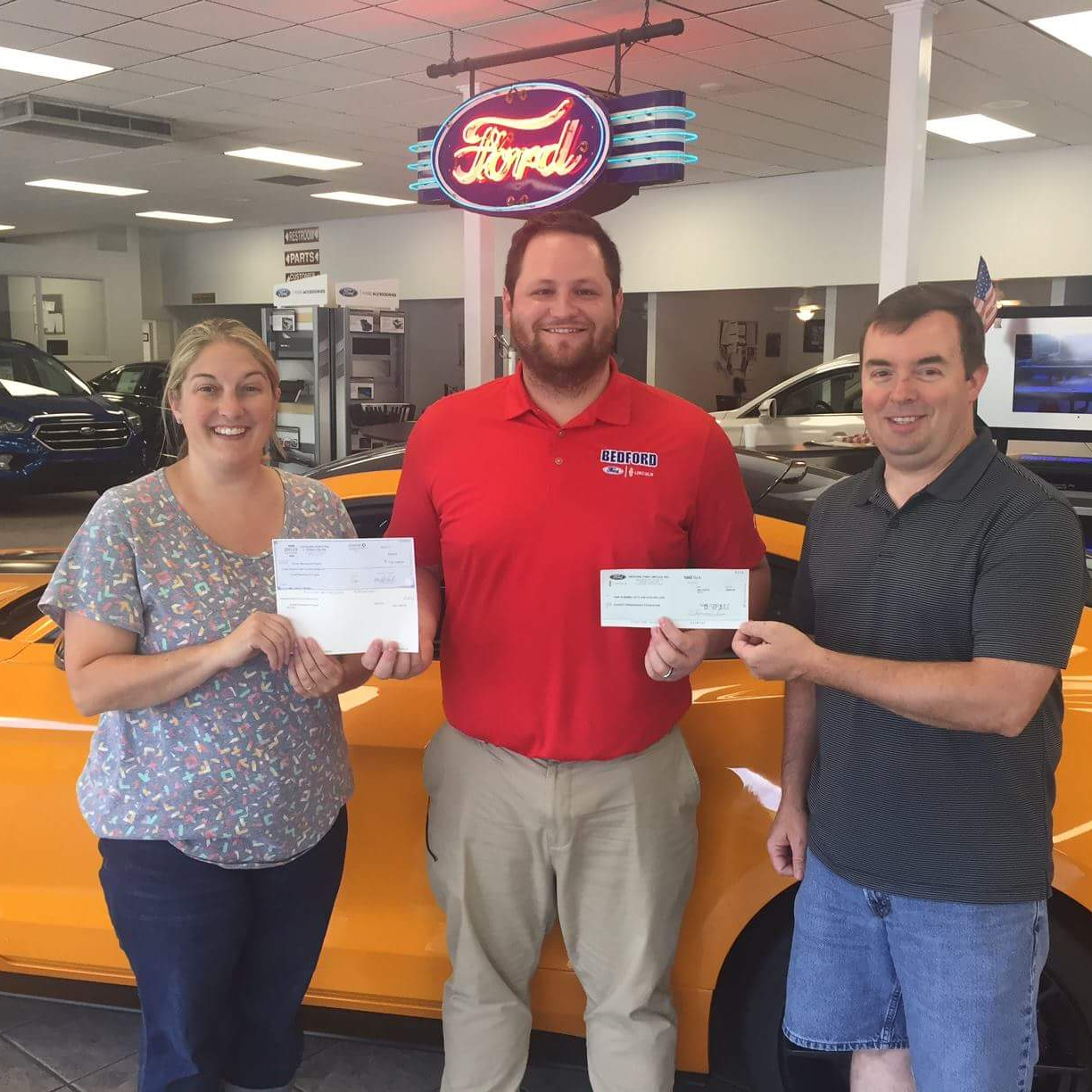 photo of three adults holding up 2 checks