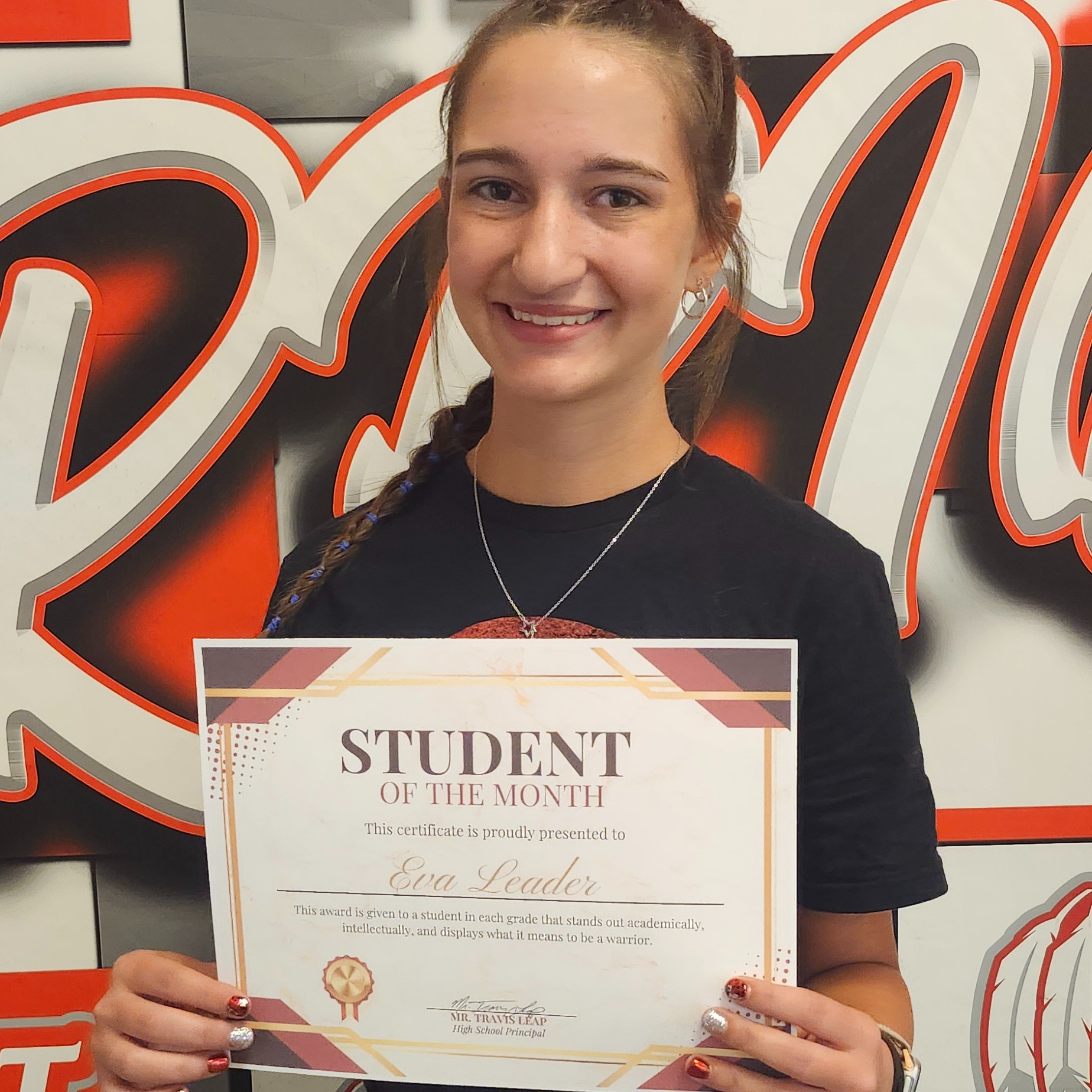 A person holds a certificate in both hands with a large sign reading "Student" behind them.