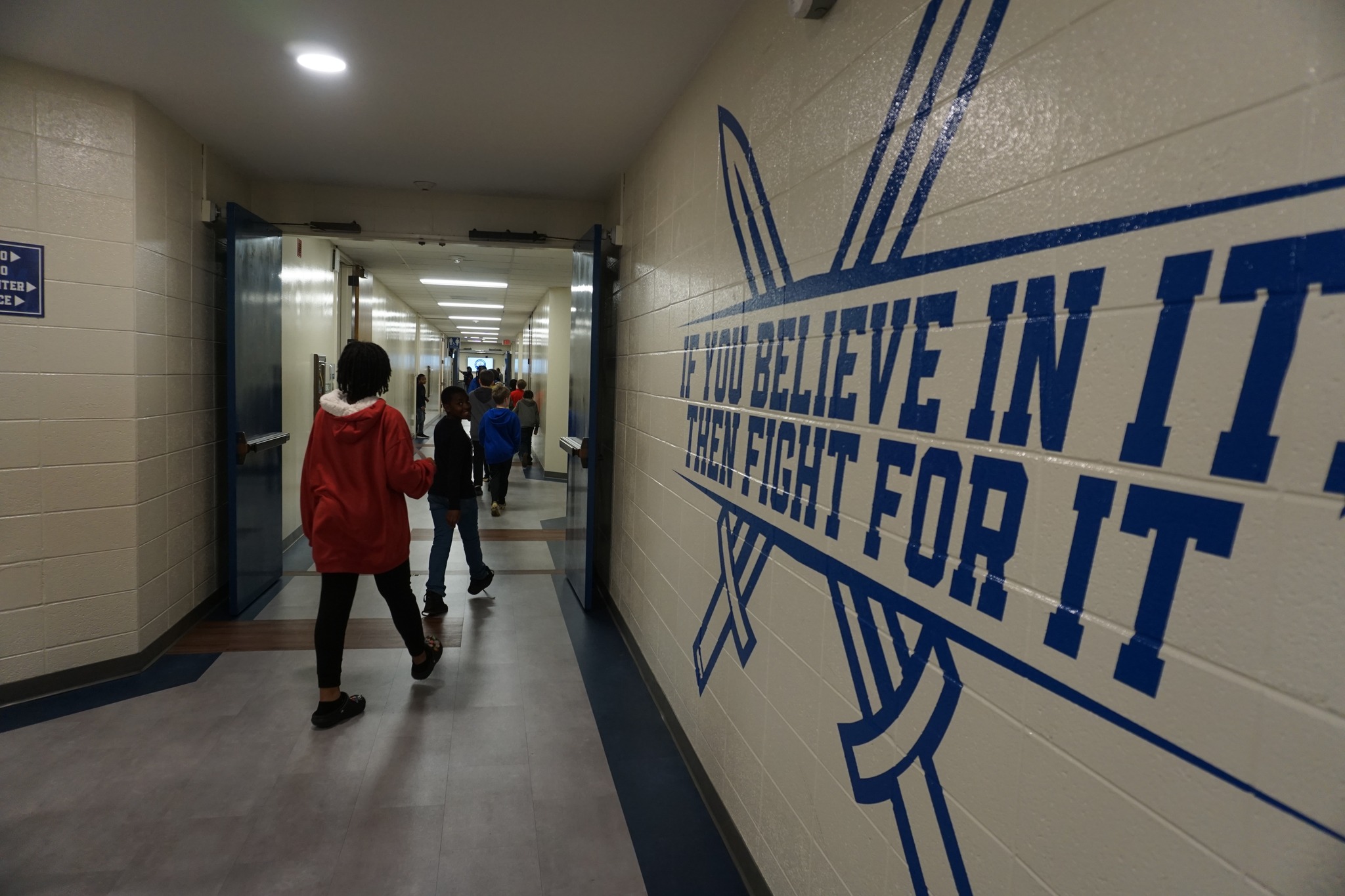 students in hallway with text "if you believe in it then fight for it"