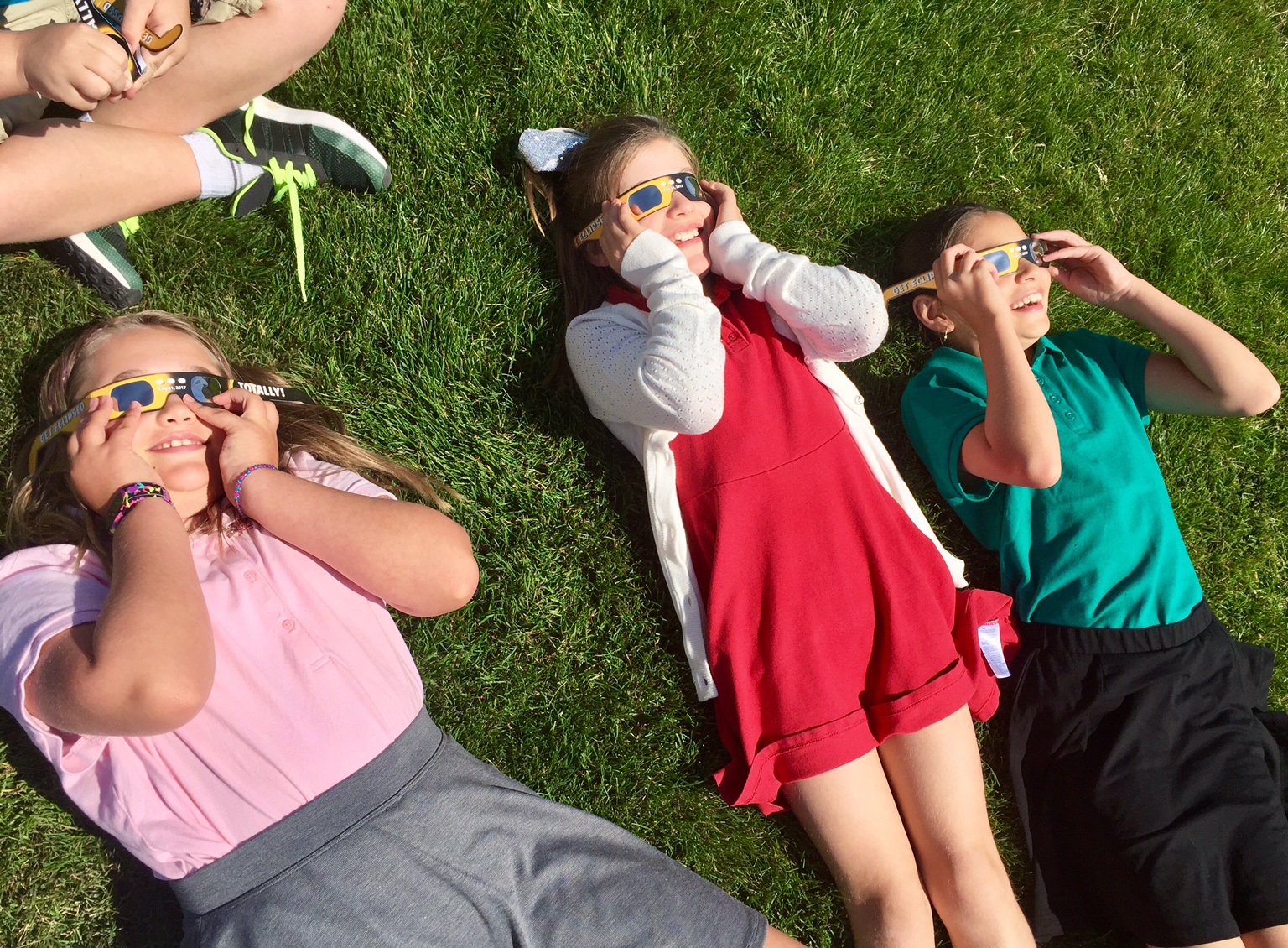 Kids lay on the grass and look at the Solar Eclipse in 2024