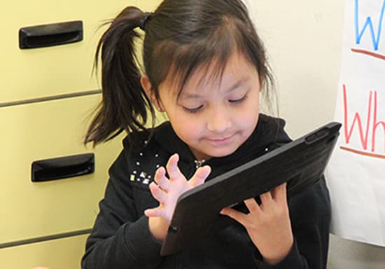 A younger girl using an iPad