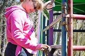 girl with pink jacket and sunglasses playing on playground