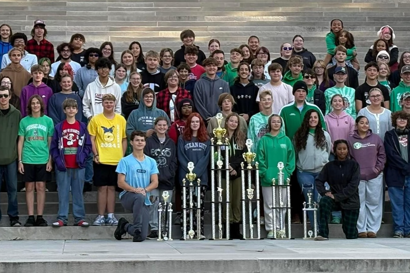 students with trophies in front of building