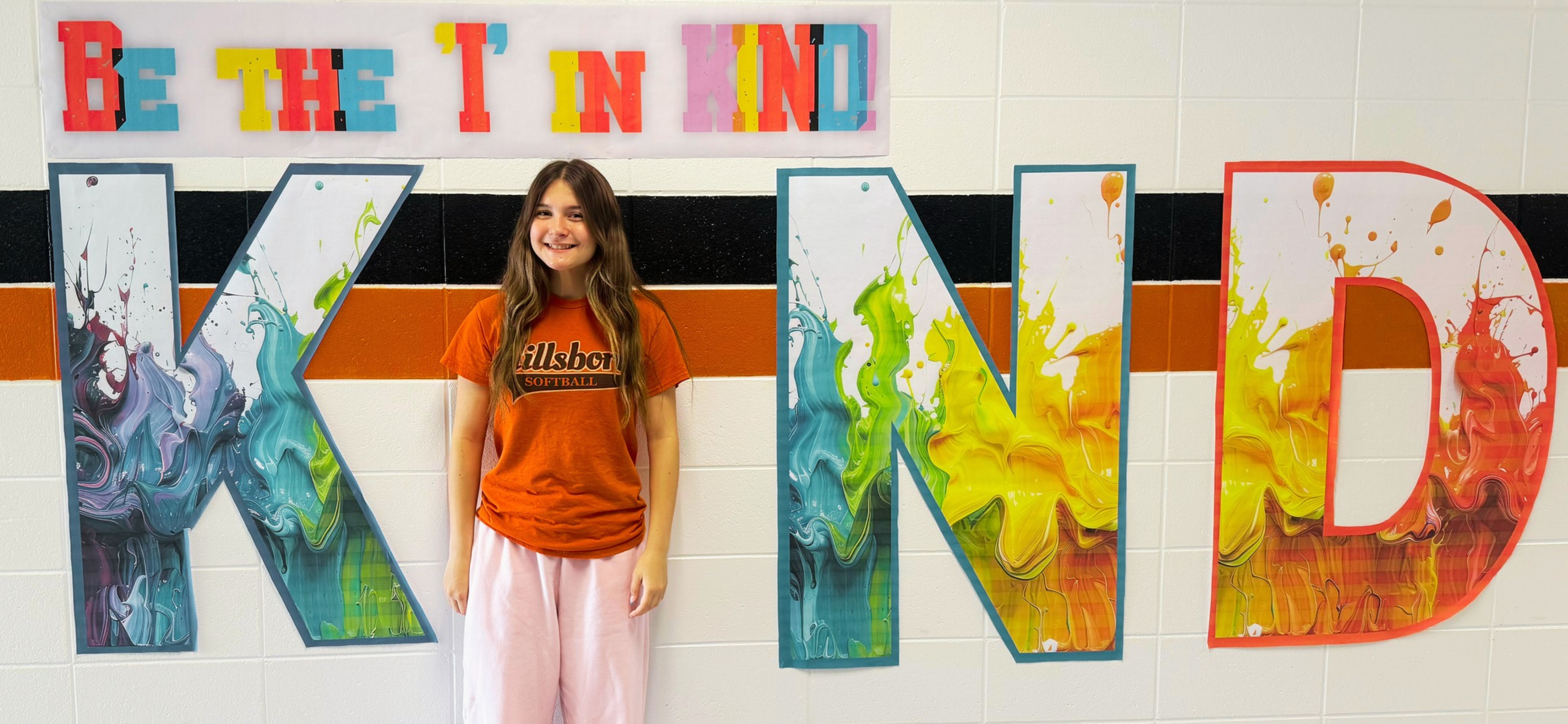 student poses with I in Kind sign