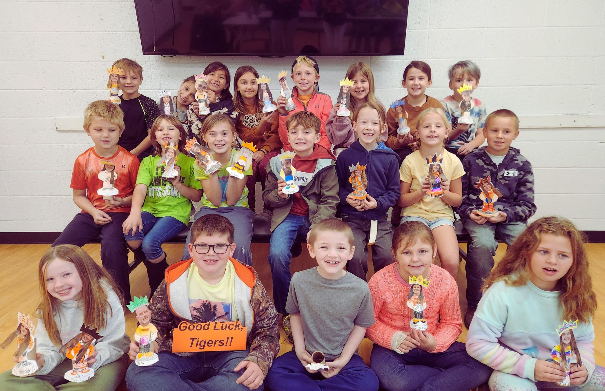 second graders pose with bobbleheads they made