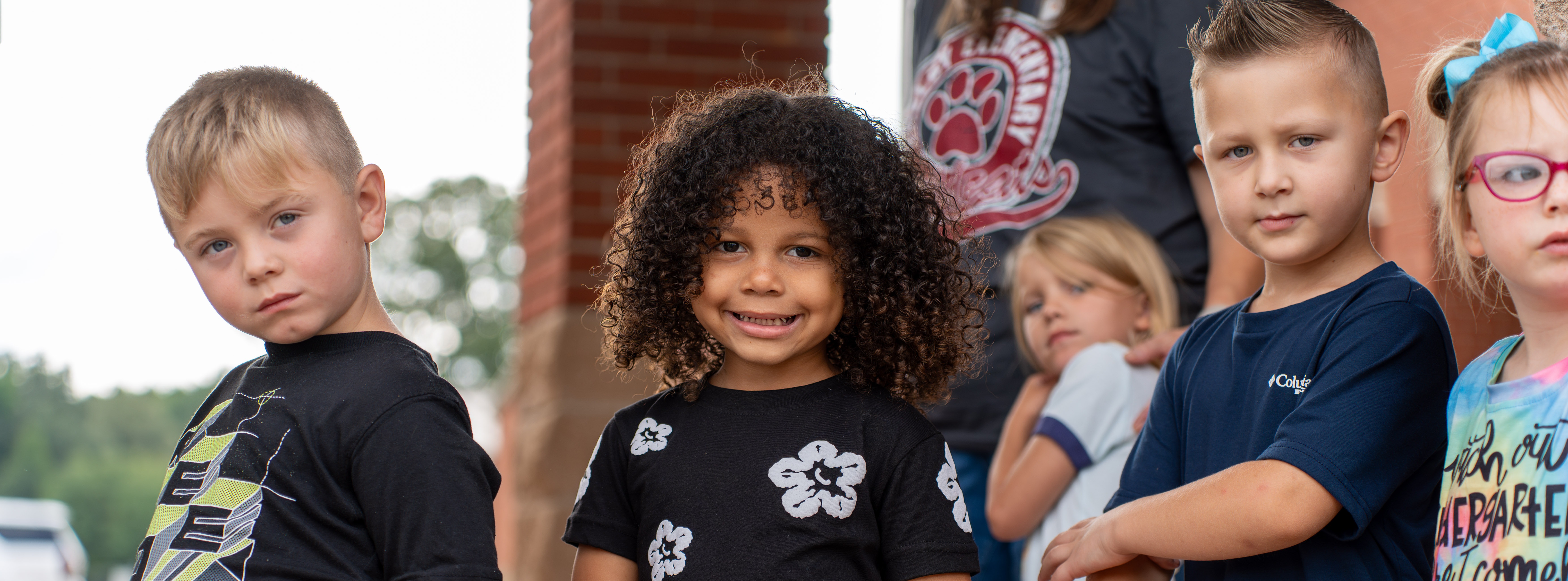 students smiling outside of school building