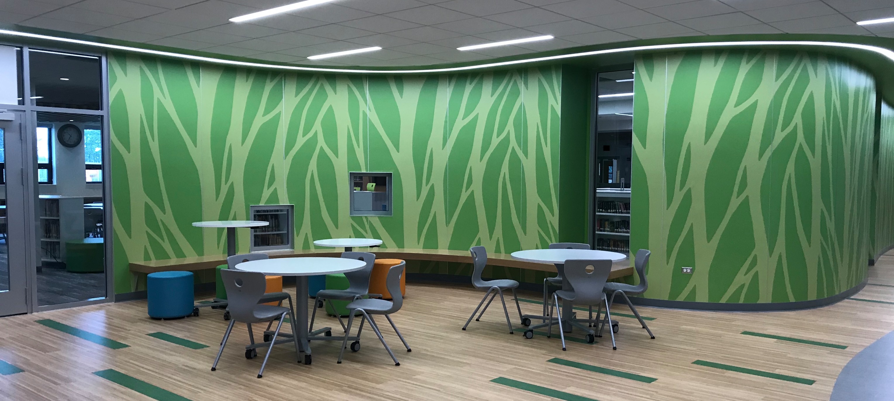 A photo of a room inside the school building with tables and chairs around them