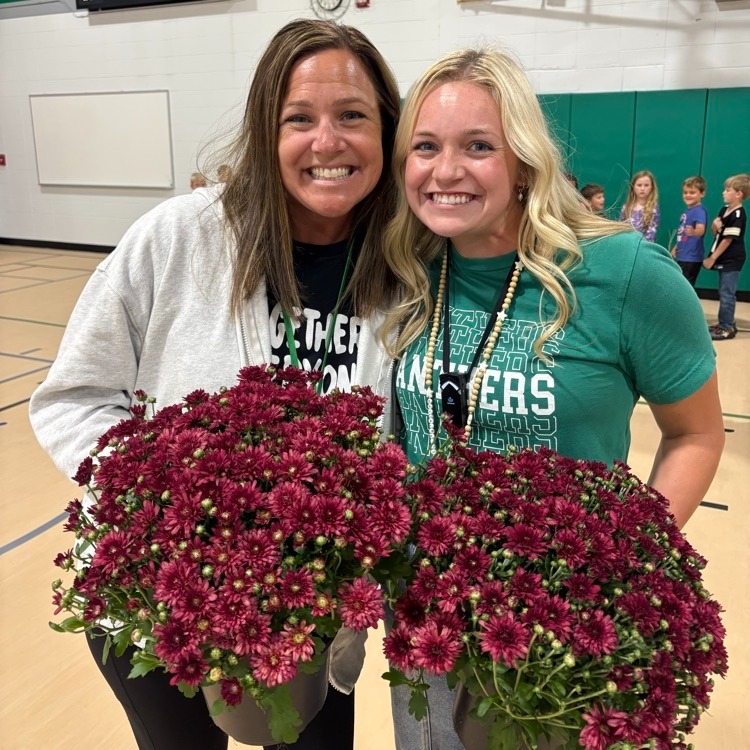 two teachers with flowers in the gym