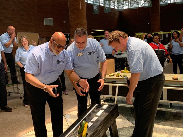 3 staff members looking at a machine and smiling at it