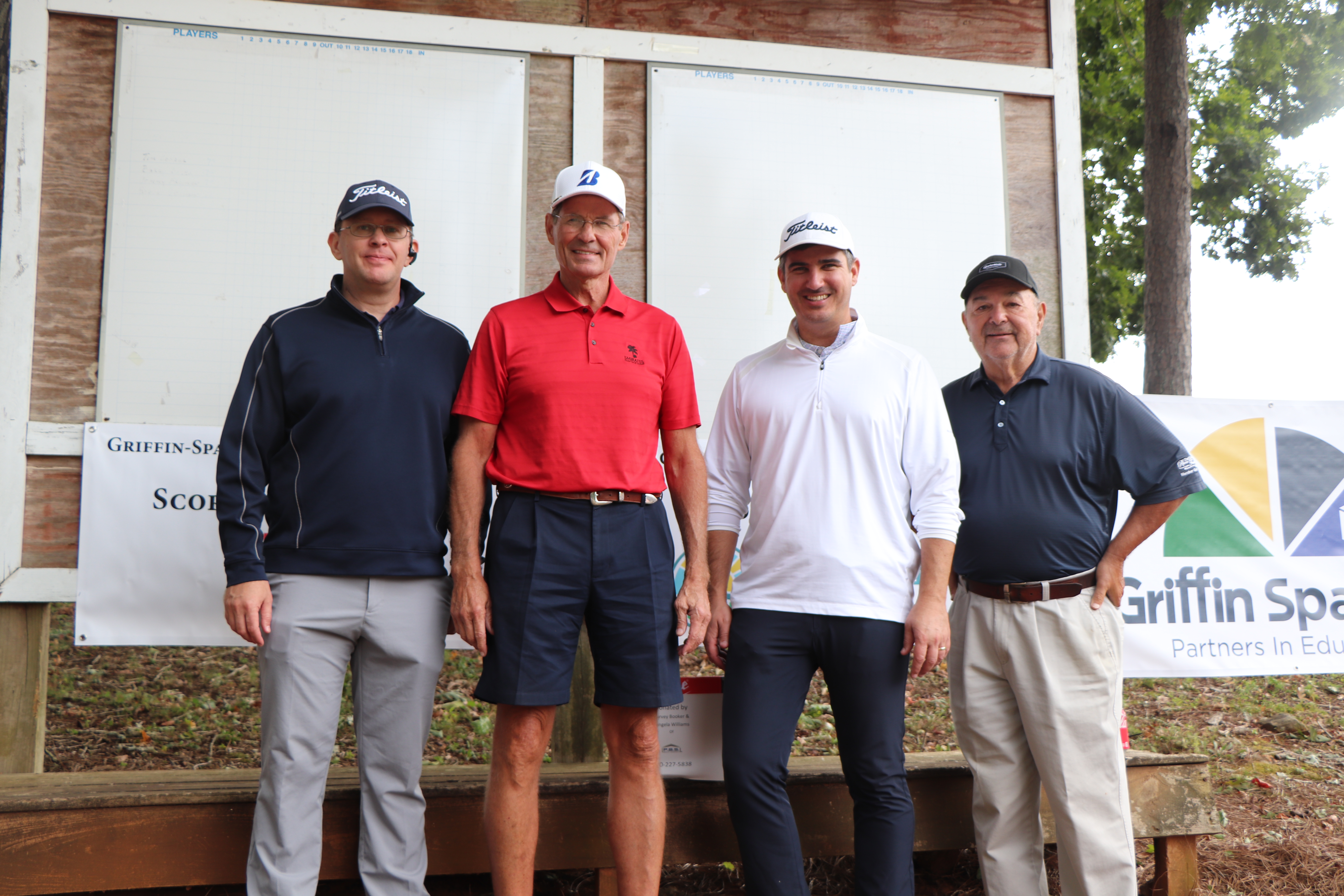 golf team posing in front of scoreboard